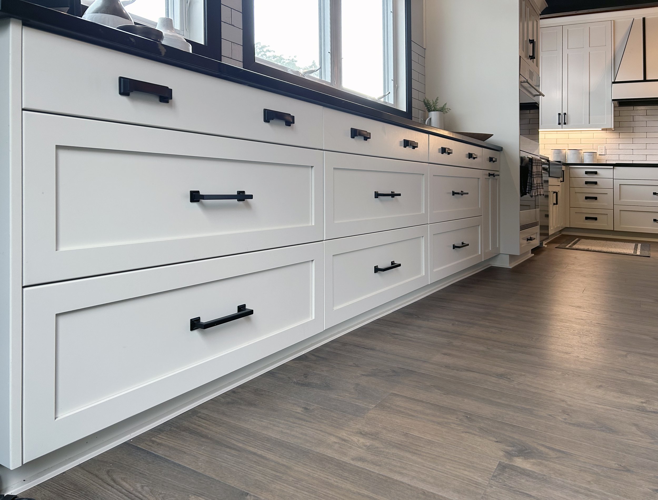 This is a modern farmhouse style kitchen and stunning wet bar. The kitchen has shaker style doors with a butcher block island top. There is a second island with extra seating that flows to the back patio. The wet bar has dark sleek cabinets with a be
