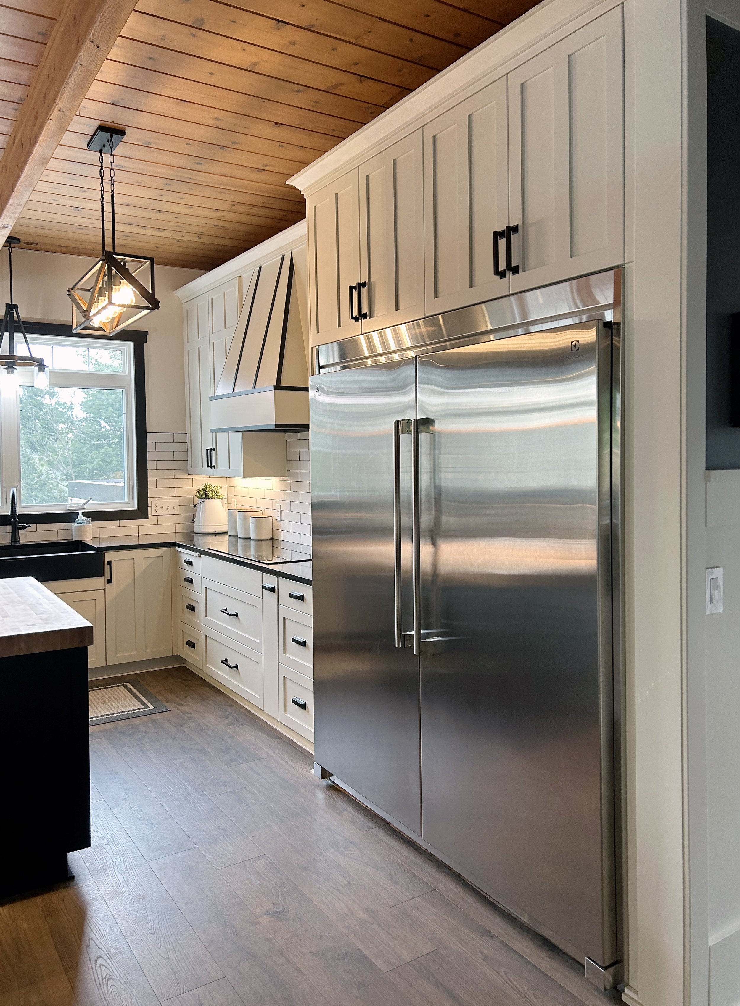 This is a modern farmhouse style kitchen and stunning wet bar. The kitchen has shaker style doors with a butcher block island top. There is a second island with extra seating that flows to the back patio. The wet bar has dark sleek cabinets with a be