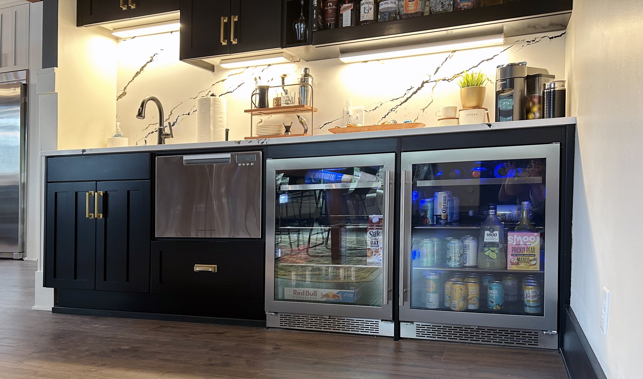 This is a modern farmhouse style kitchen and stunning wet bar. The kitchen has shaker style doors with a butcher block island top. There is a second island with extra seating that flows to the back patio. The wet bar has dark sleek cabinets with a be
