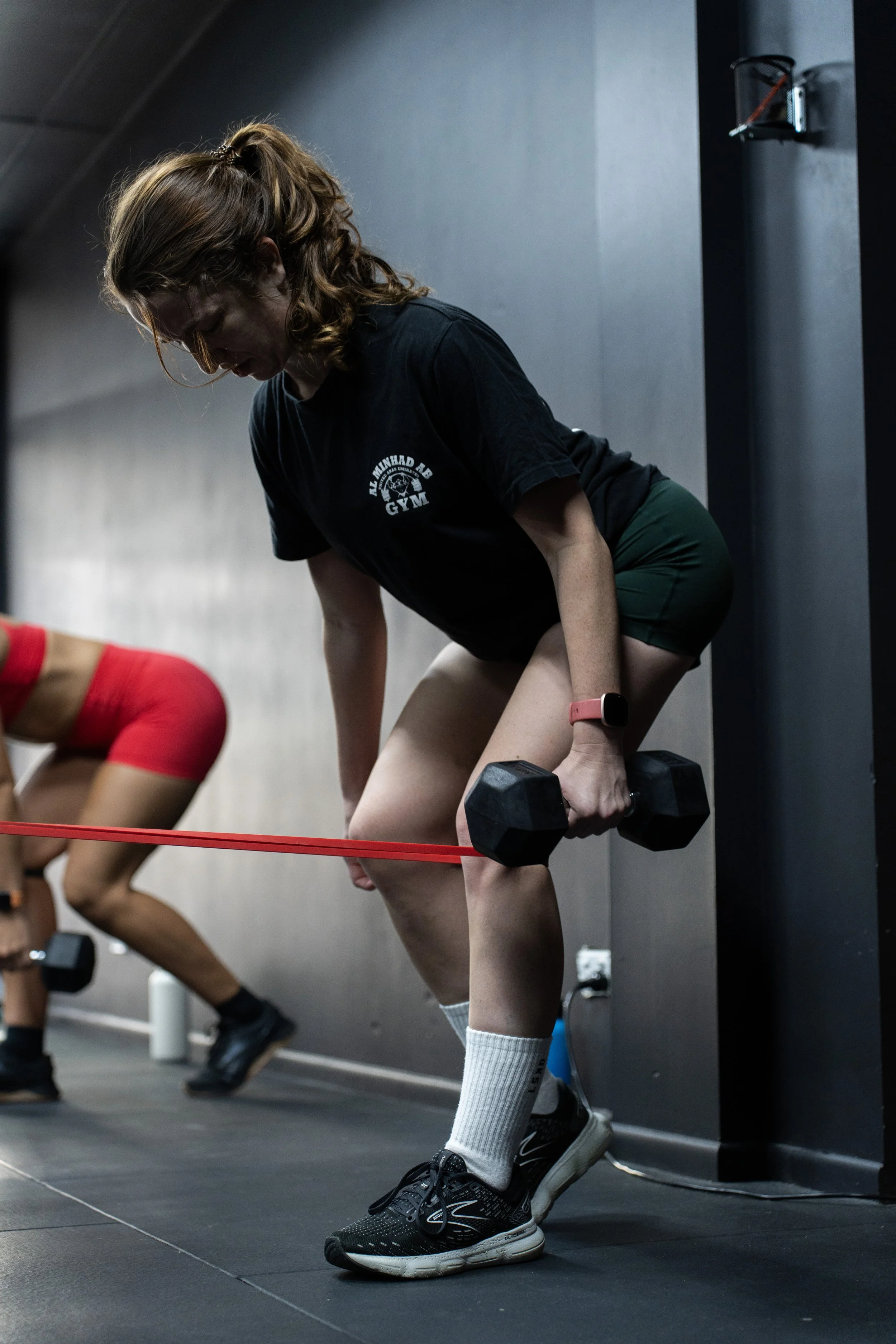 Woman in workout clothes lifting a dumbbell during resistance training in a gym. Redemption Training small group fitness and strength/cardio gym in Albion, North Brisbane. For all ages including over 40.