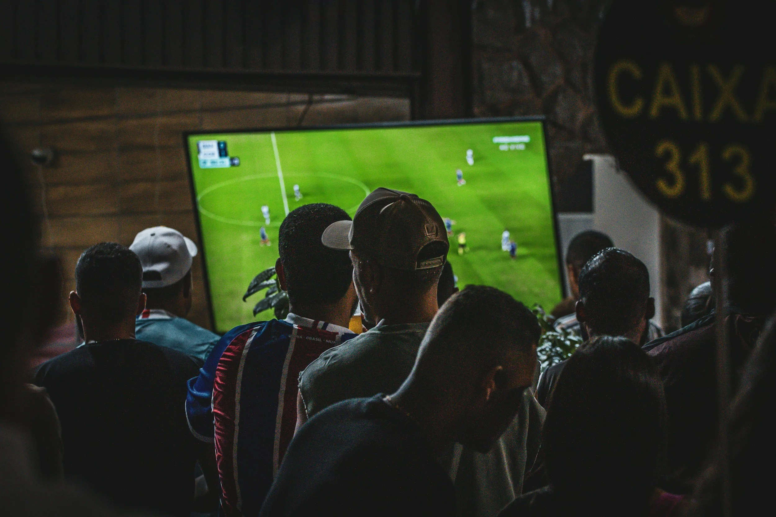 People in a pub looking at televised football match