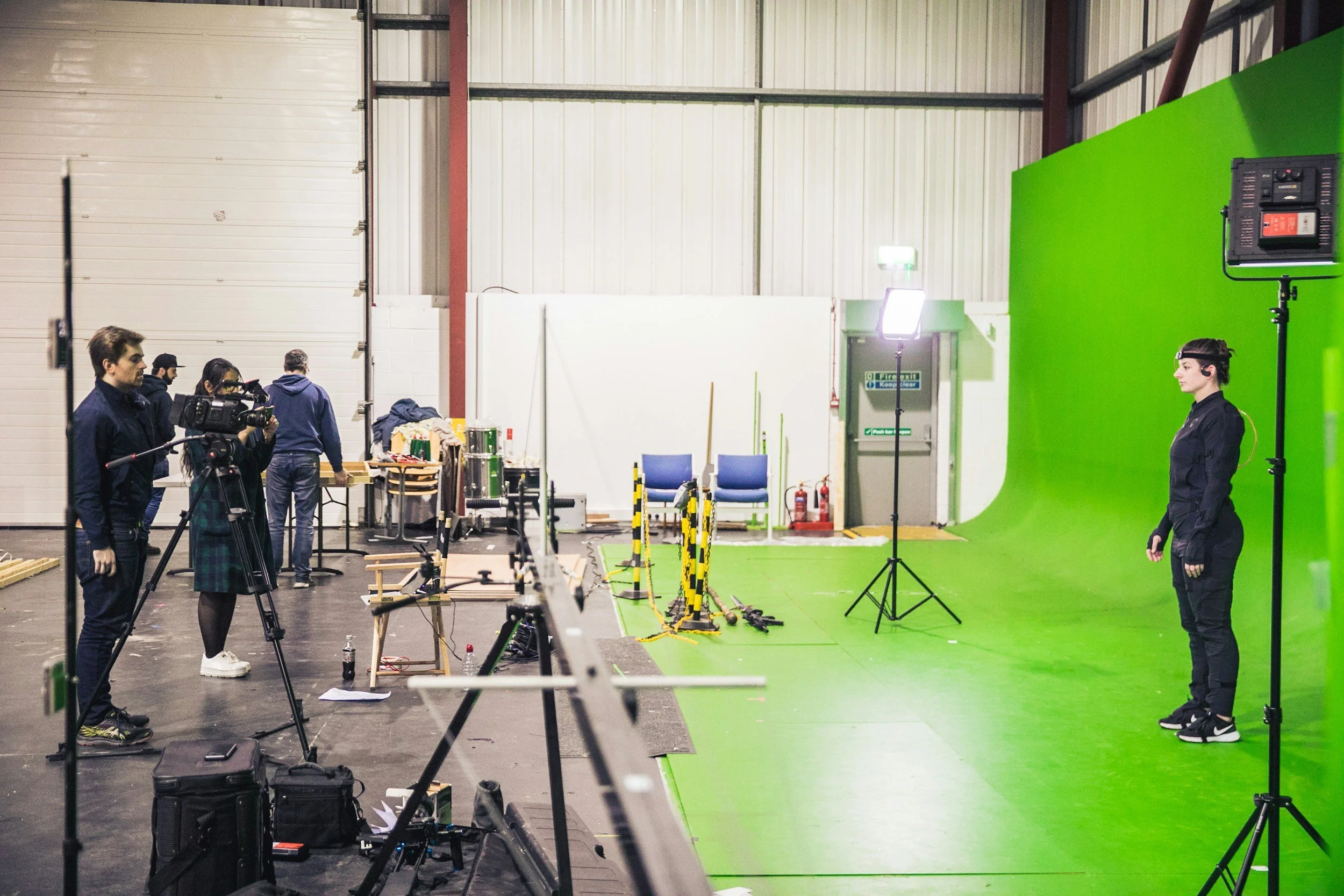 A filming crew in a set with a green screen