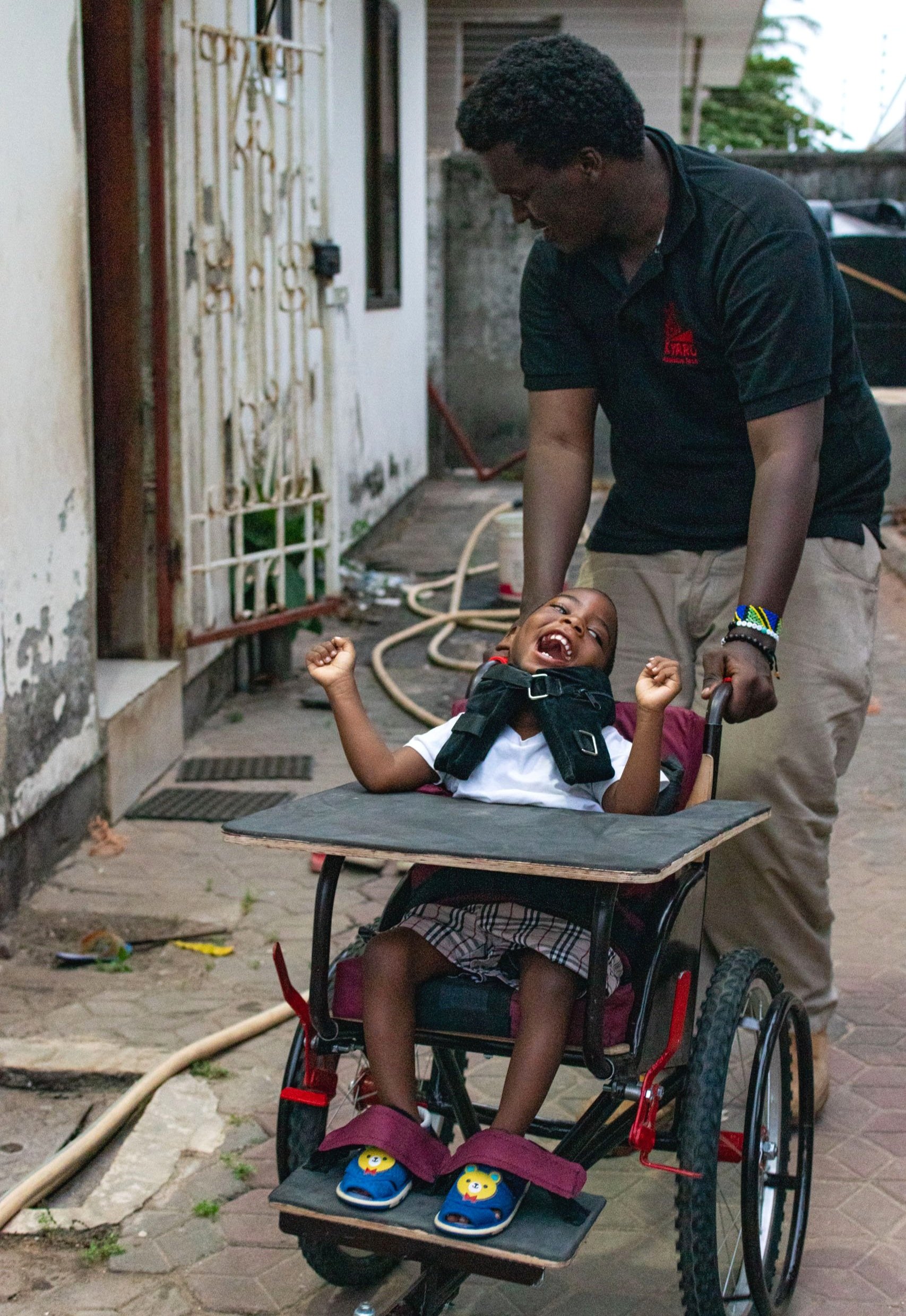 A little boy laughing, sitting in a wheelchair