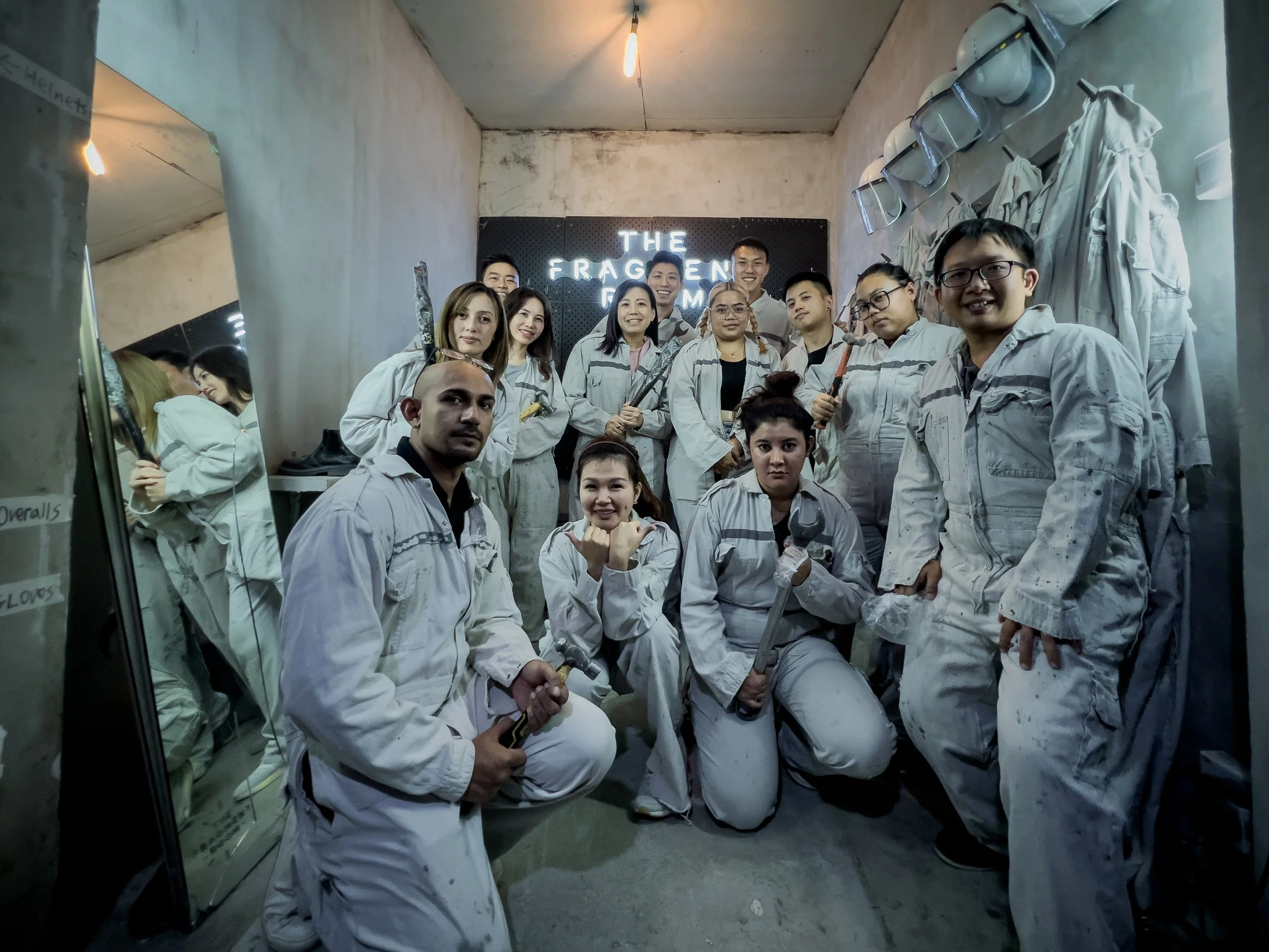 Group of people wearing white jumpsuits in a room with a sign that reads "The Fragrant Room" in the background, some holding tools, posing for a photo.