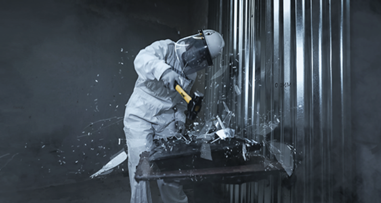 Worker in protective gear cutting metal with a power saw, sparks flying