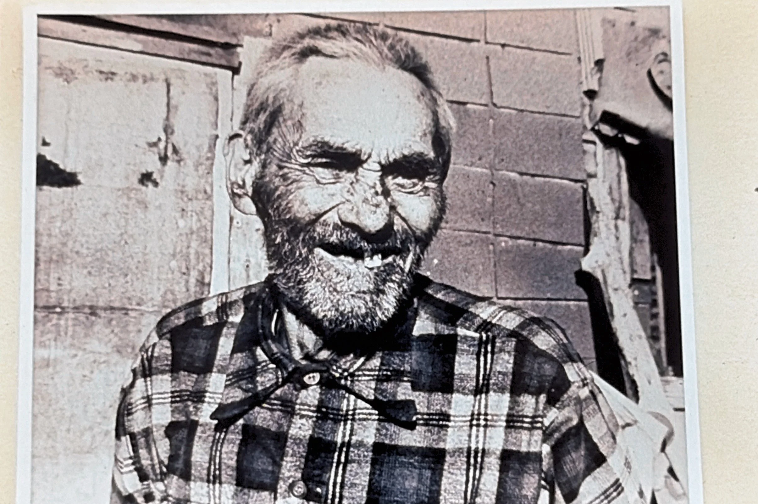 Image of an elderly man with a plaid shirt and missing teeth