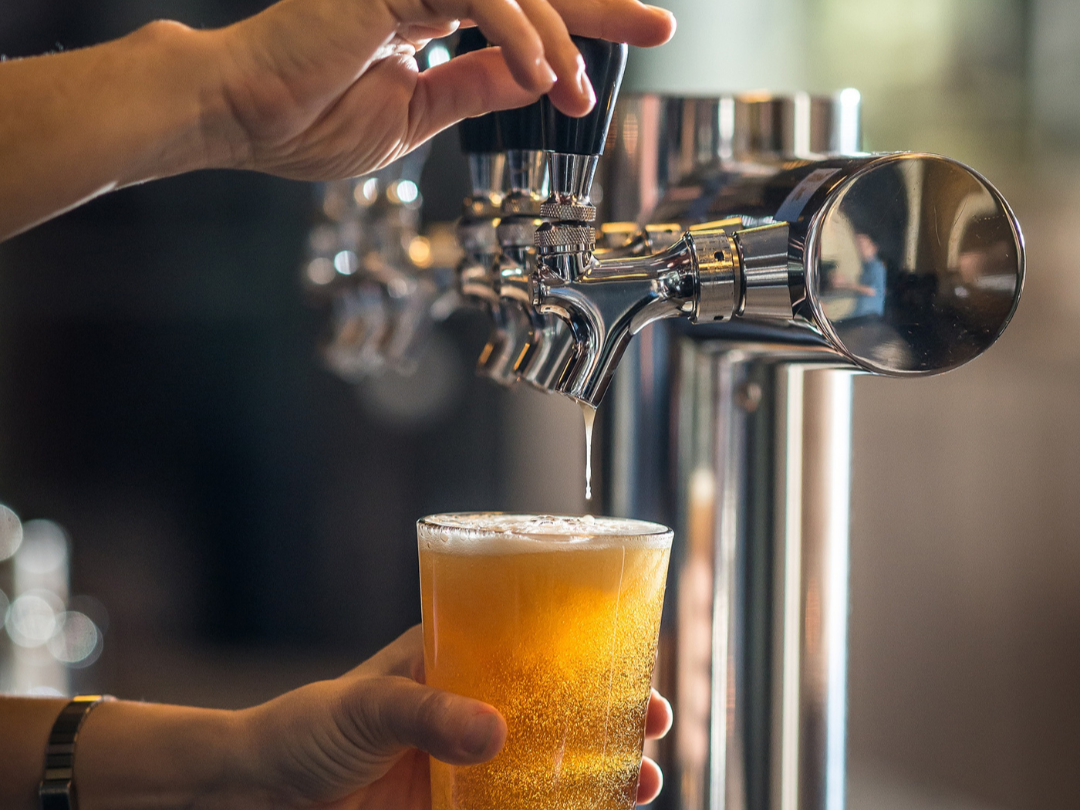 woman's hand pouring beer out of a tap