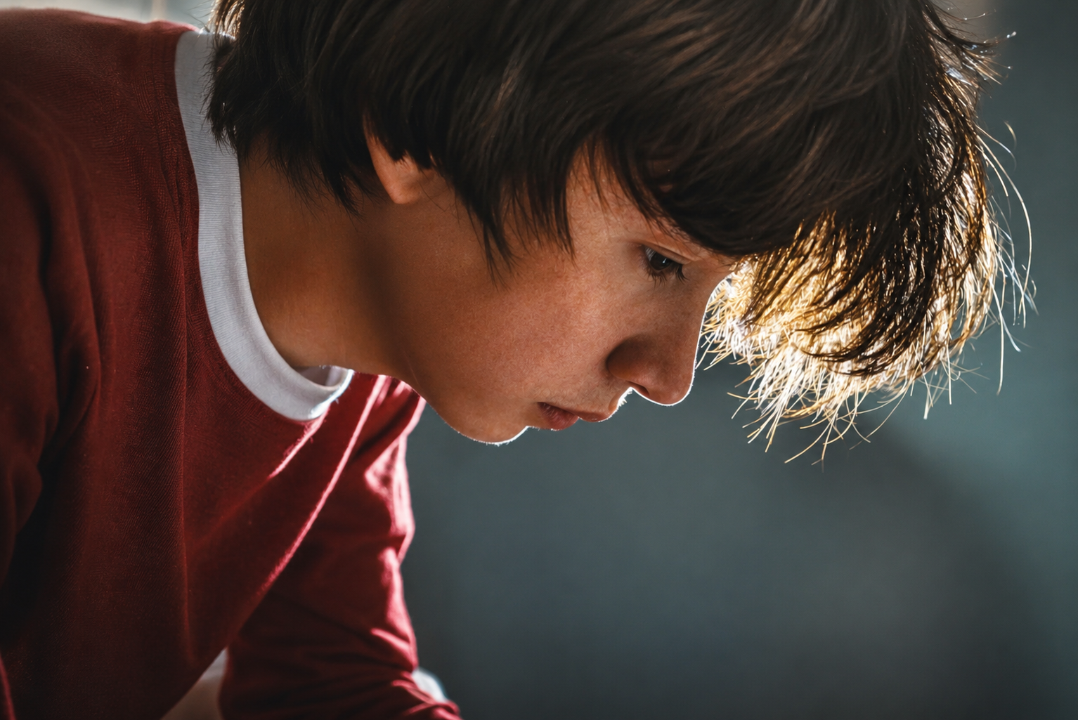 Teen sitting alone and looking down, illustrating anxiety, loneliness, and emotional challenges that can affect adolescent mental health during summer break.