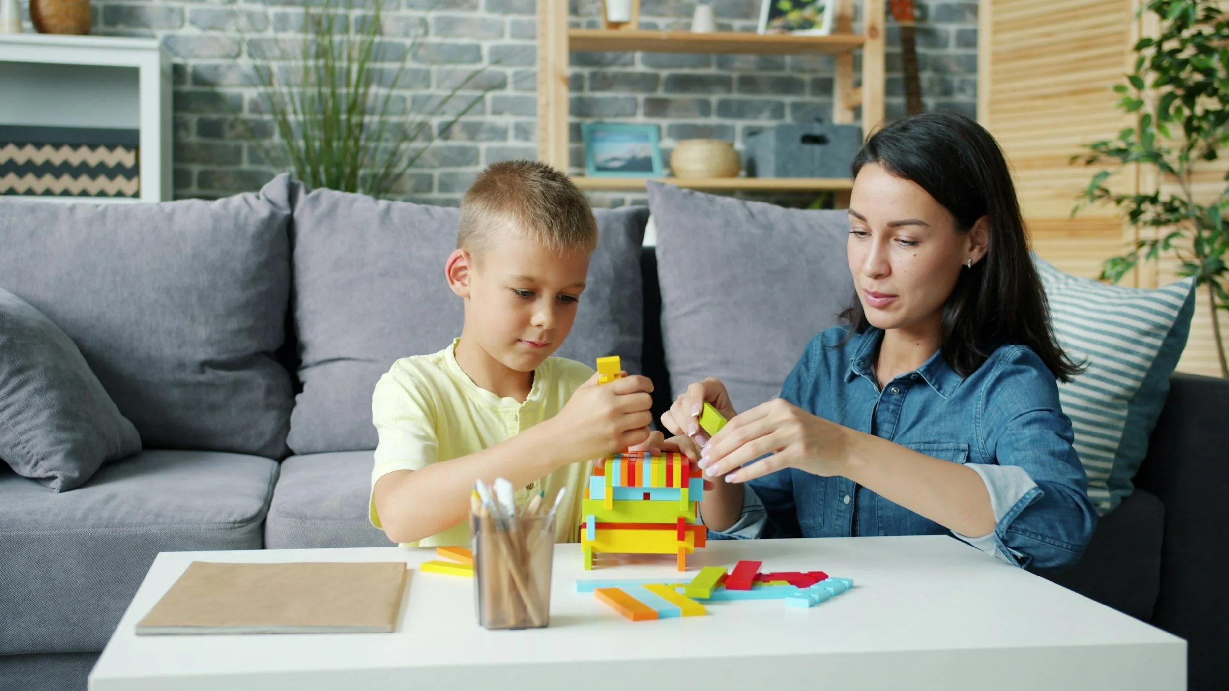 A child and therapist building a colorful block structure together during a play therapy session in a warm, welcoming office.