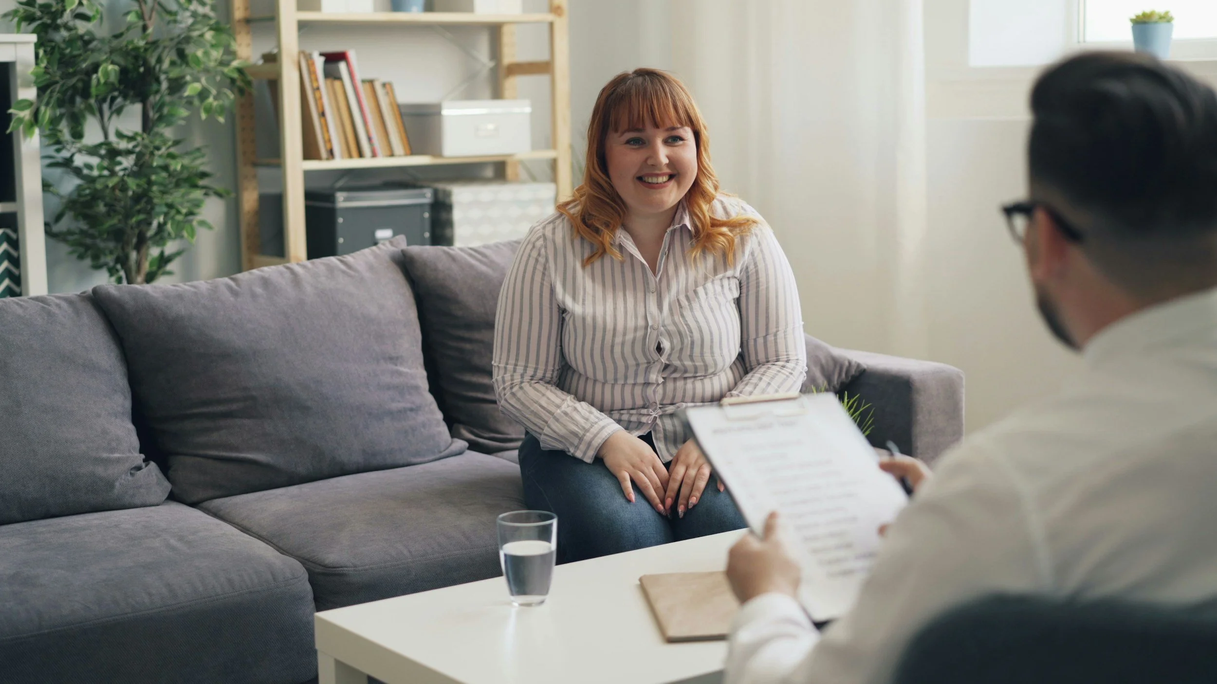 Person smiling while talking with a therapist during a counseling session in a comfortable office.