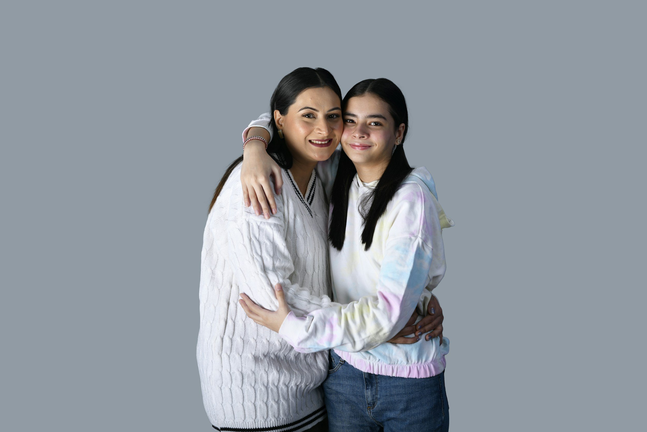Mother hugging her LGBTQ+ teenage daughter in a supportive and affirming family relationship