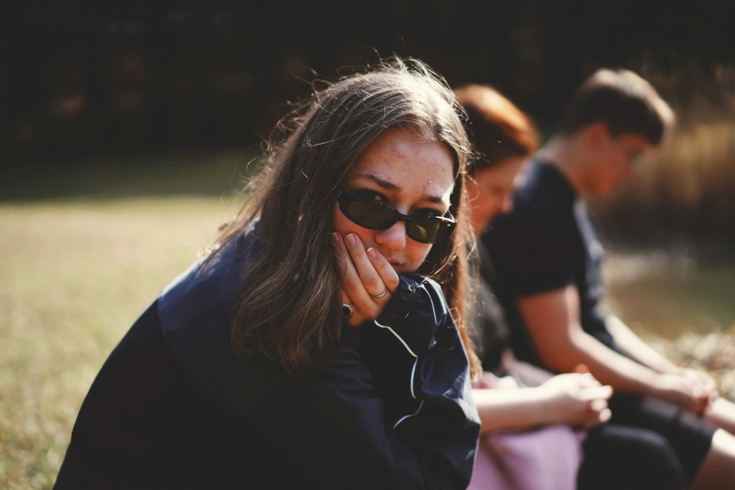 Thoughtful teenager sitting apart from others, representing the emotional challenges LGBTQ+ youth may face in religious families
