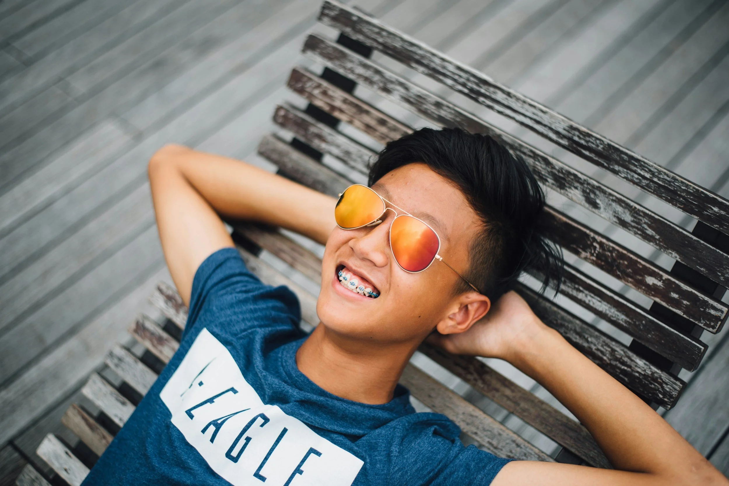 Teen relaxing outdoors and smiling, representing emotional well-being, resilience, and positive mental health during adolescence.