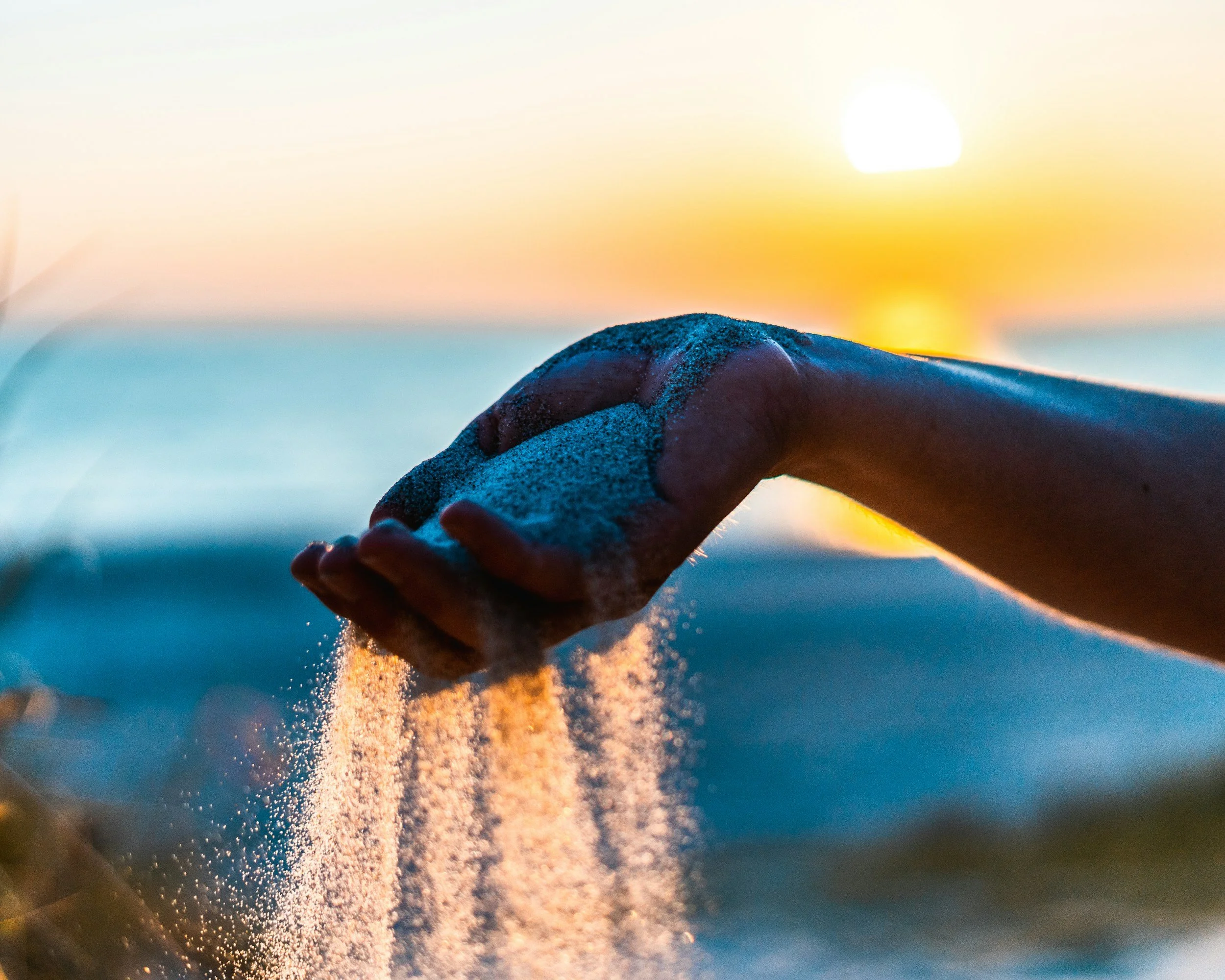 Sand slipping through a person's hands, symbolizing letting go of what you can't control and focusing your energy on your own thoughts, choices, and responses.