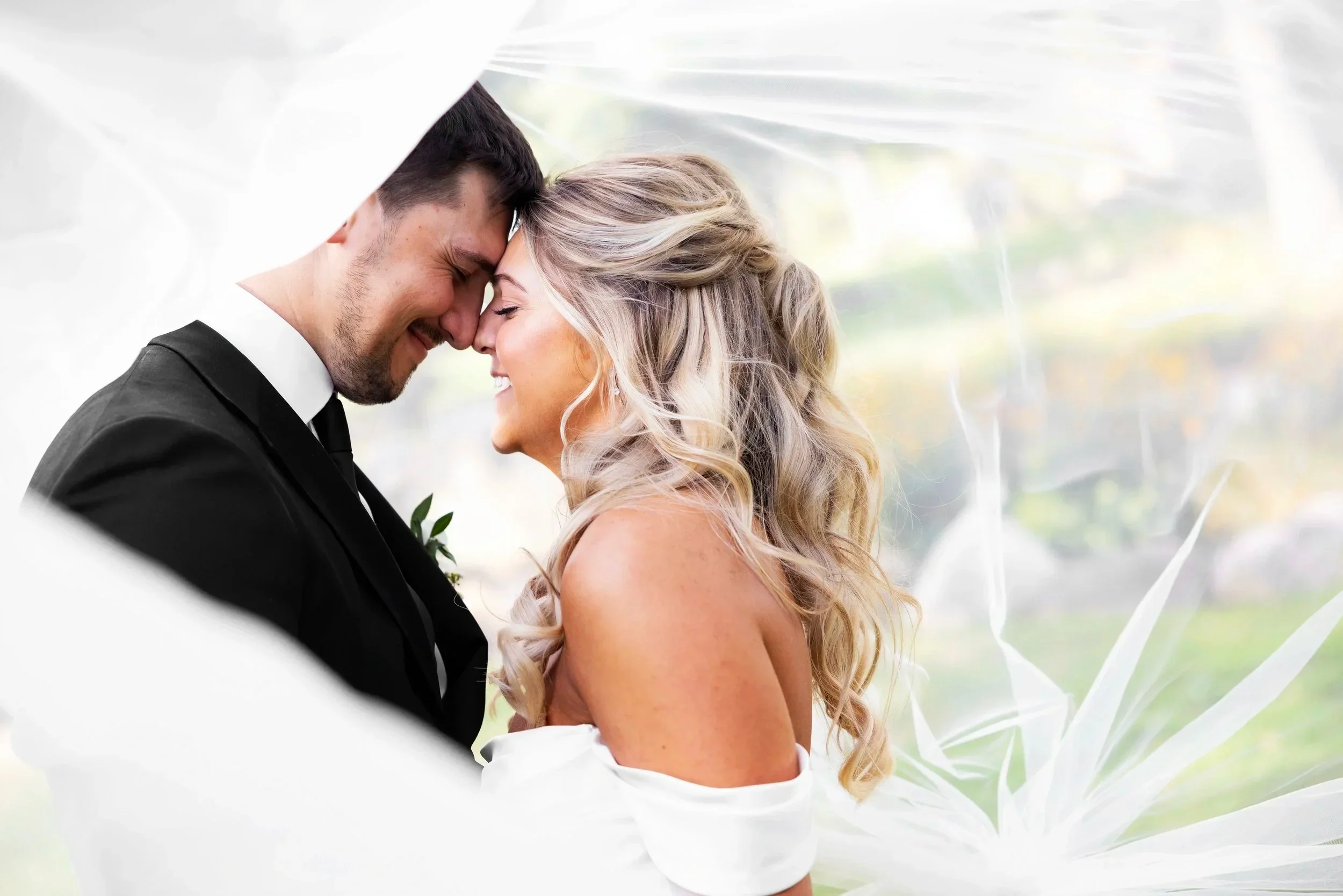 Bride and groom smiling beneath the veil outside Pine Knob Mansion in Clarkston, Michigan
