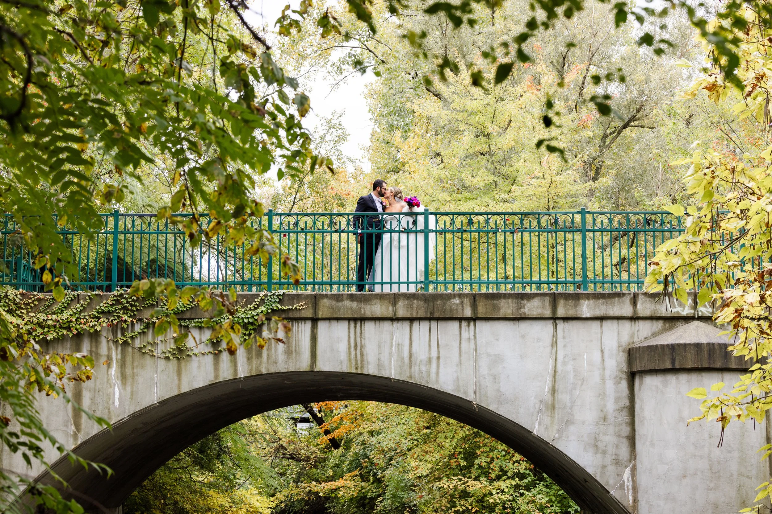 Bride and groom kiss on bridge at Royal Park Hotel in Rochester, MI