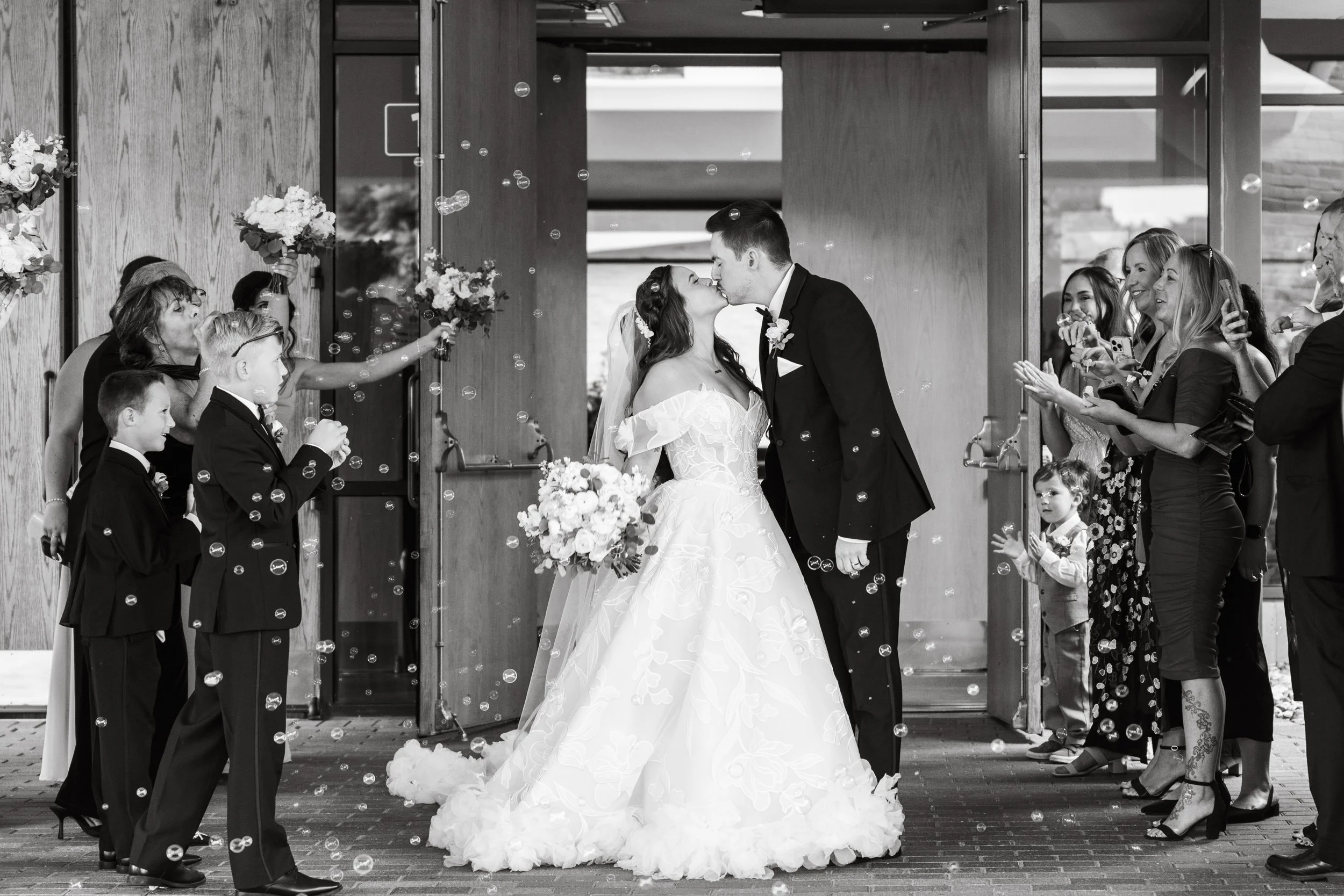 Bride and Groom Kiss During Bubble Exit Outside Church 