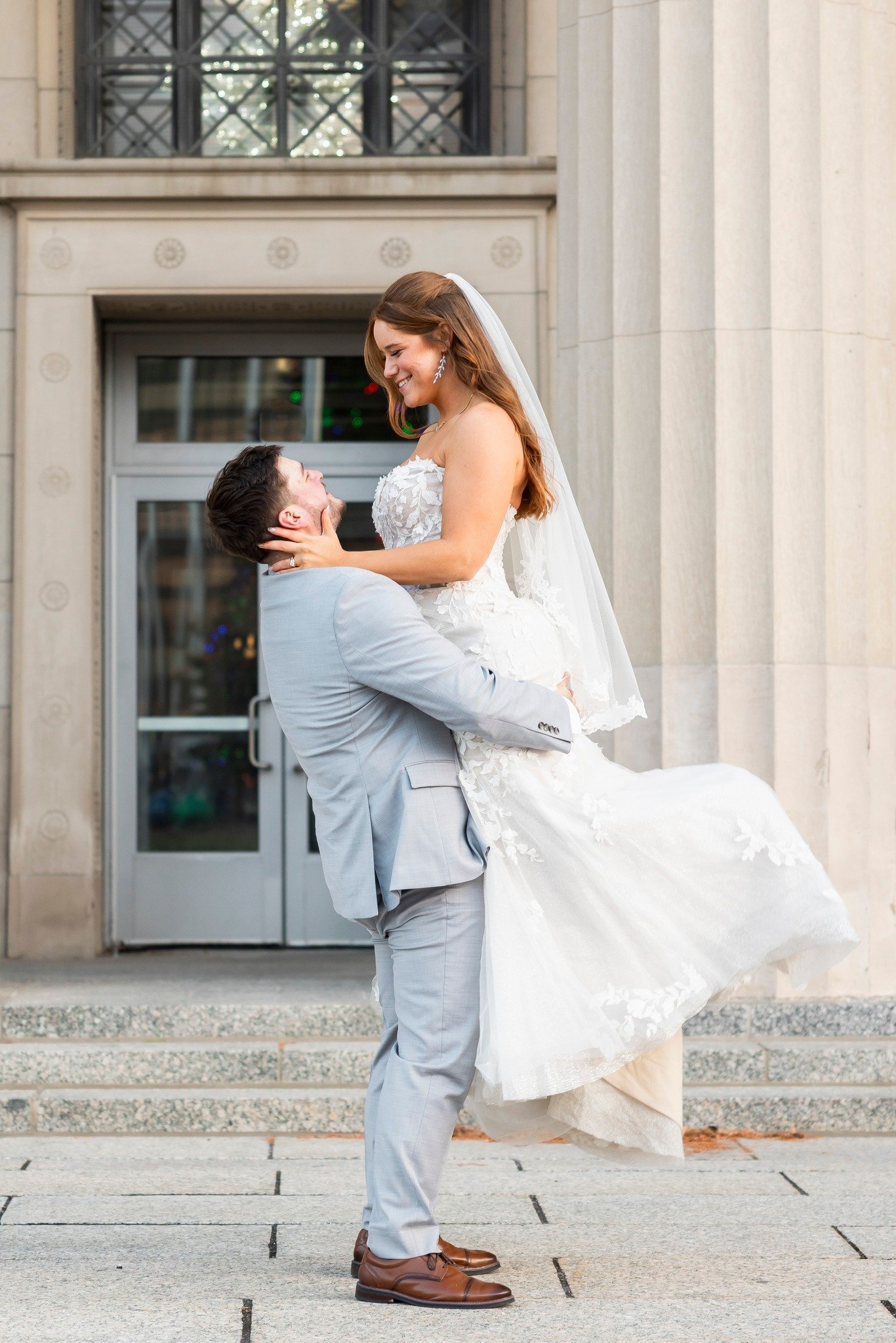 romantic wedding photo of groom holding bride outside the jackson commonwealth center in michigan