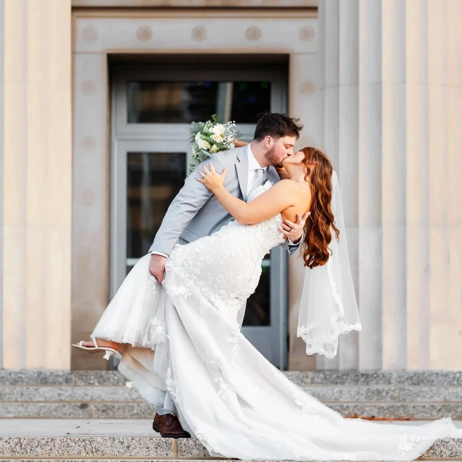 romantic wedding photo of groom holding bride outside the jackson commonwealth center in michigan