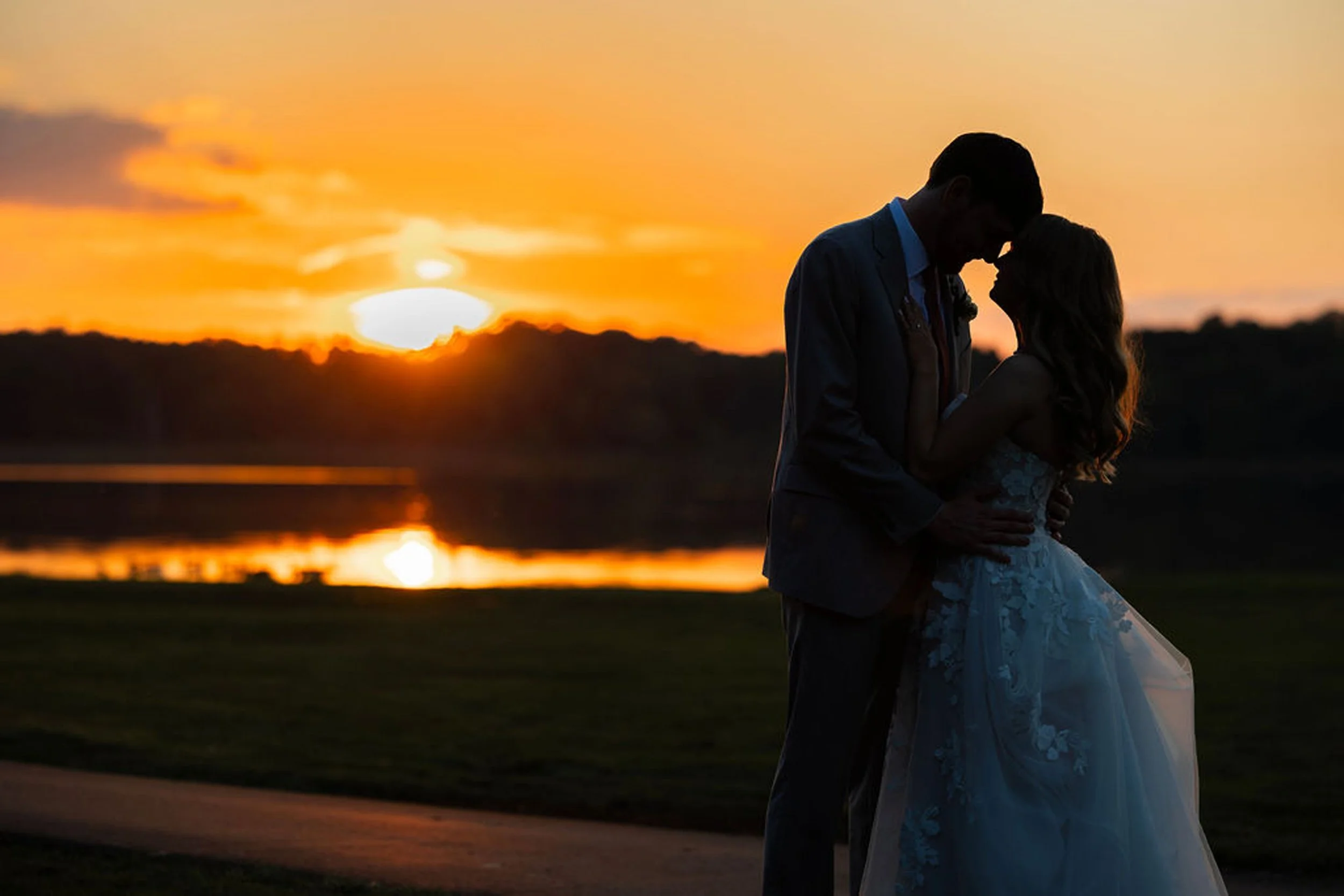 Bride and groom embrace in front of sunset at Waldenwoods in Howell, MI