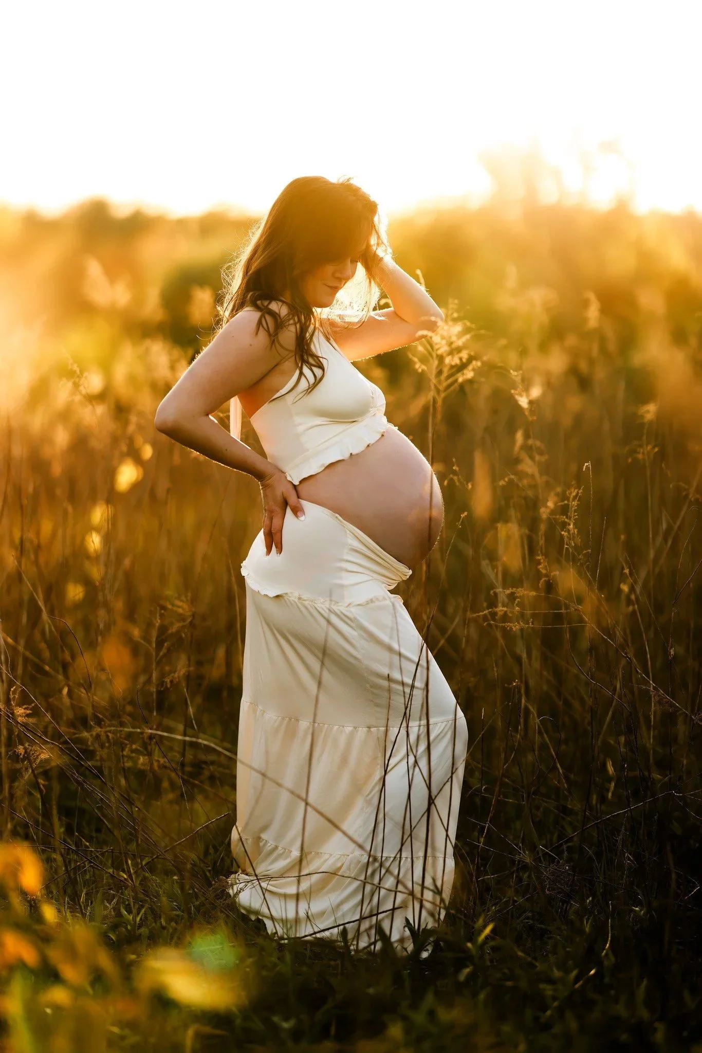 pregnant woman posing outside in fenton michigan during golden hour