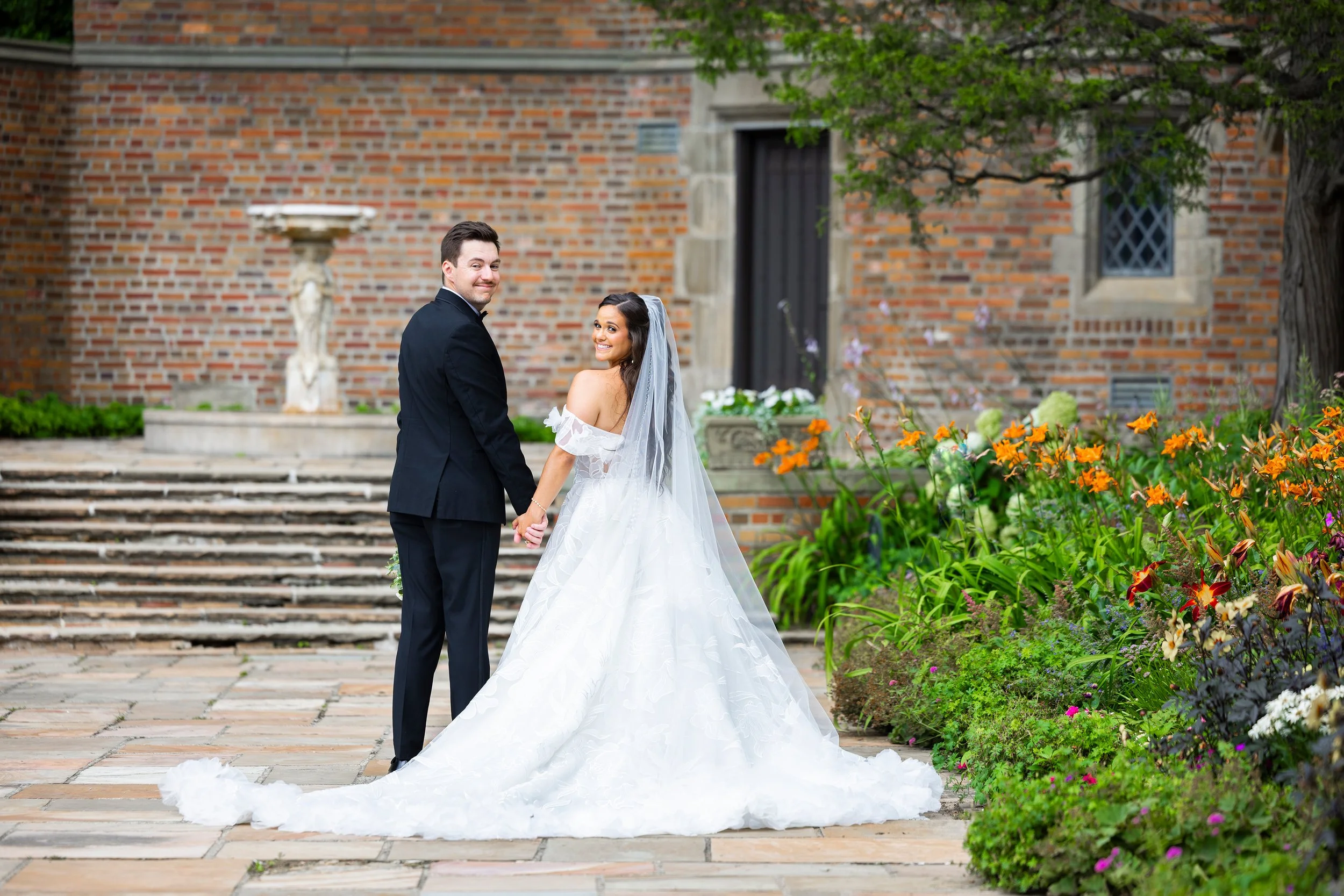 Bride and groom look back while walking away at Meadow Brook Hall in Rochester, Michigan