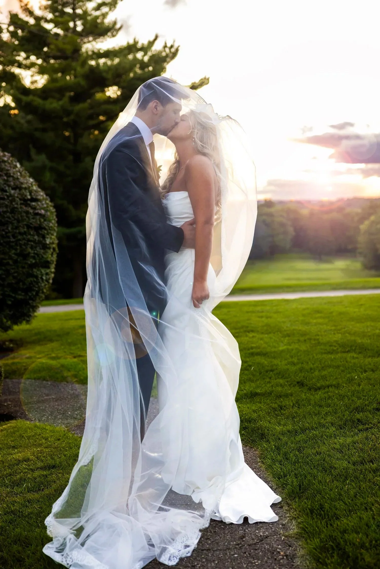bride and groom kissing under veil during golden hour at Pine Knob Mansion in Clarkston, Michigan