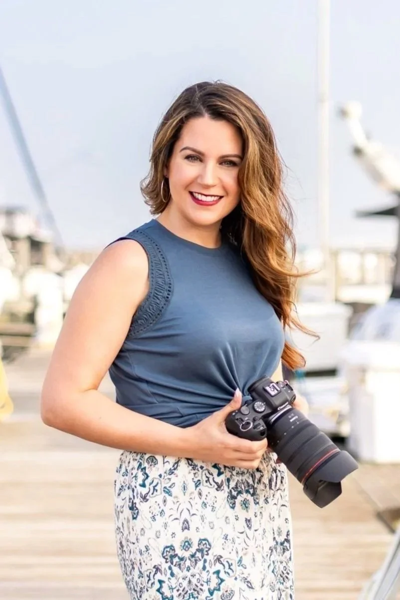 Outdoor portrait of wedding and portrait photographer Lola Marie Helka holding her camera in Michigan