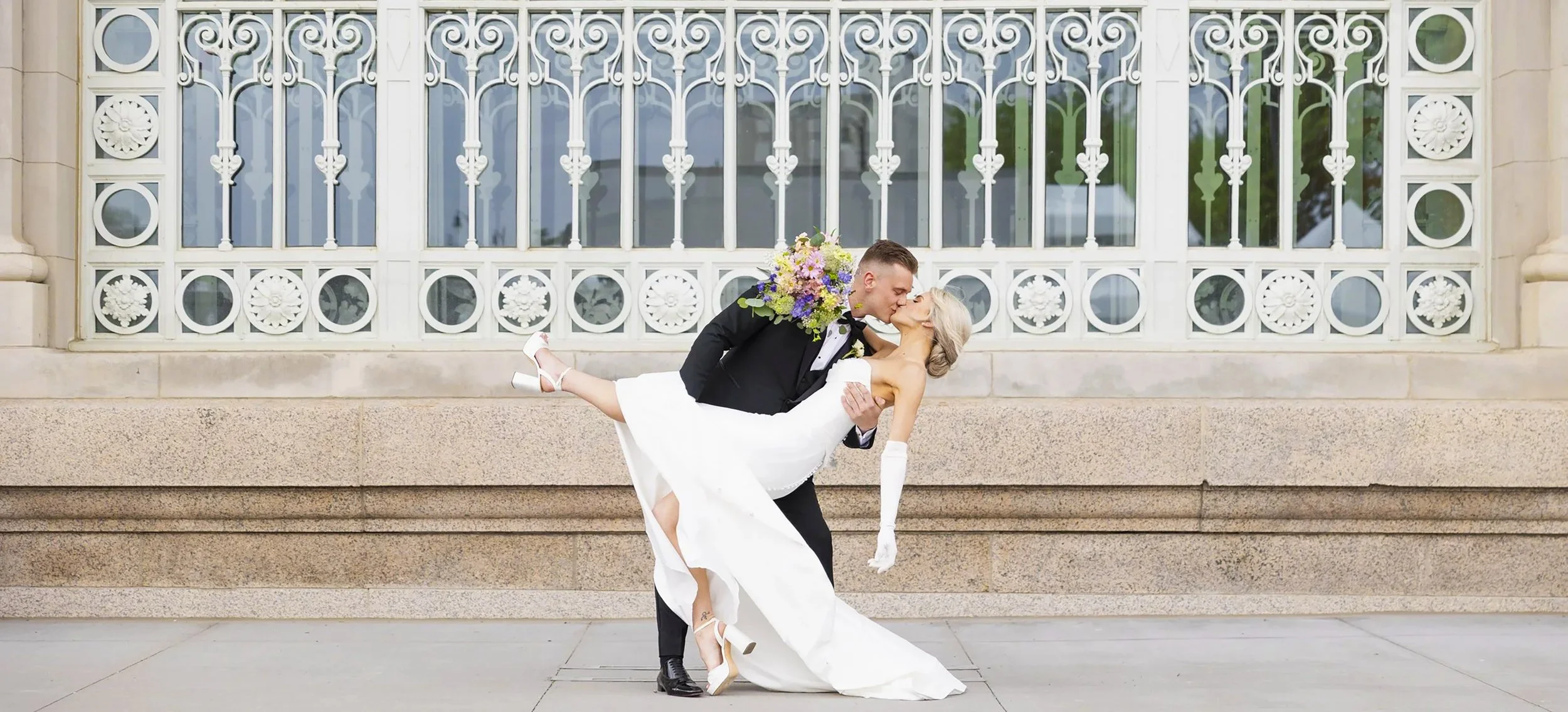 Groom dipping his bride for a kiss outside Michigan Central Station in downtown Detroit