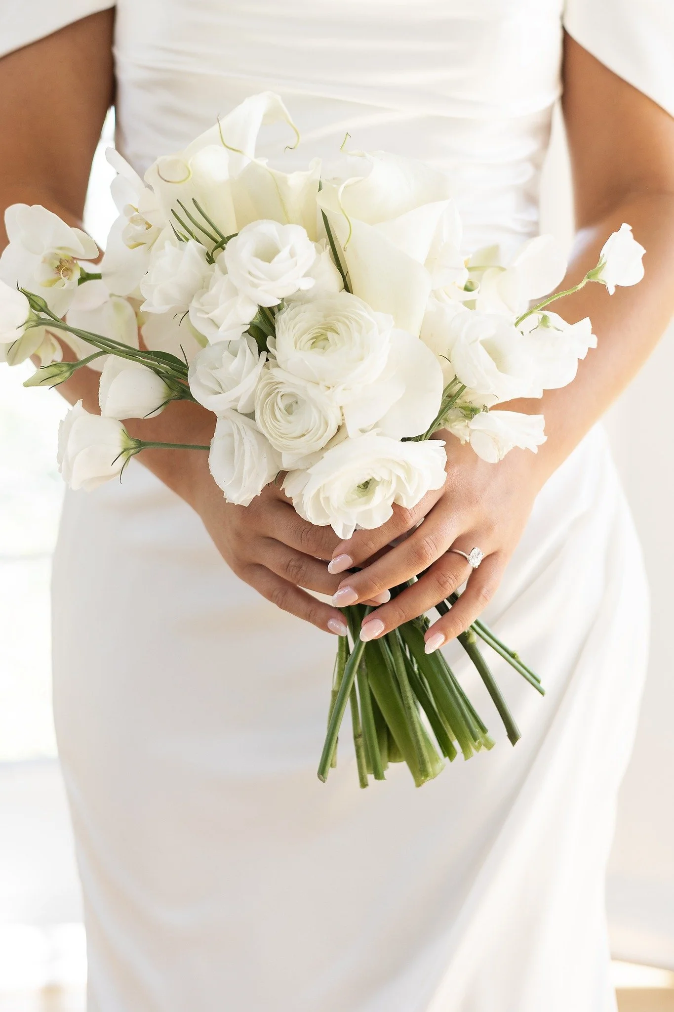 close up wedding photo of bride's hands holding bouquet with elegant ring