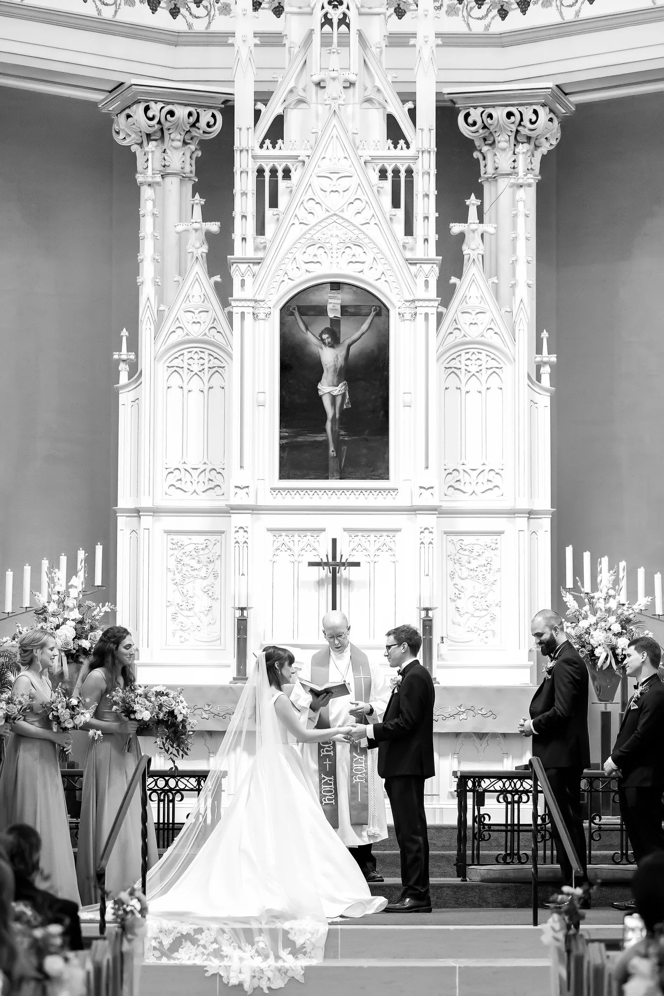 Elegant black and white ceremony picture of bride and groom taking vows in a beautiful church