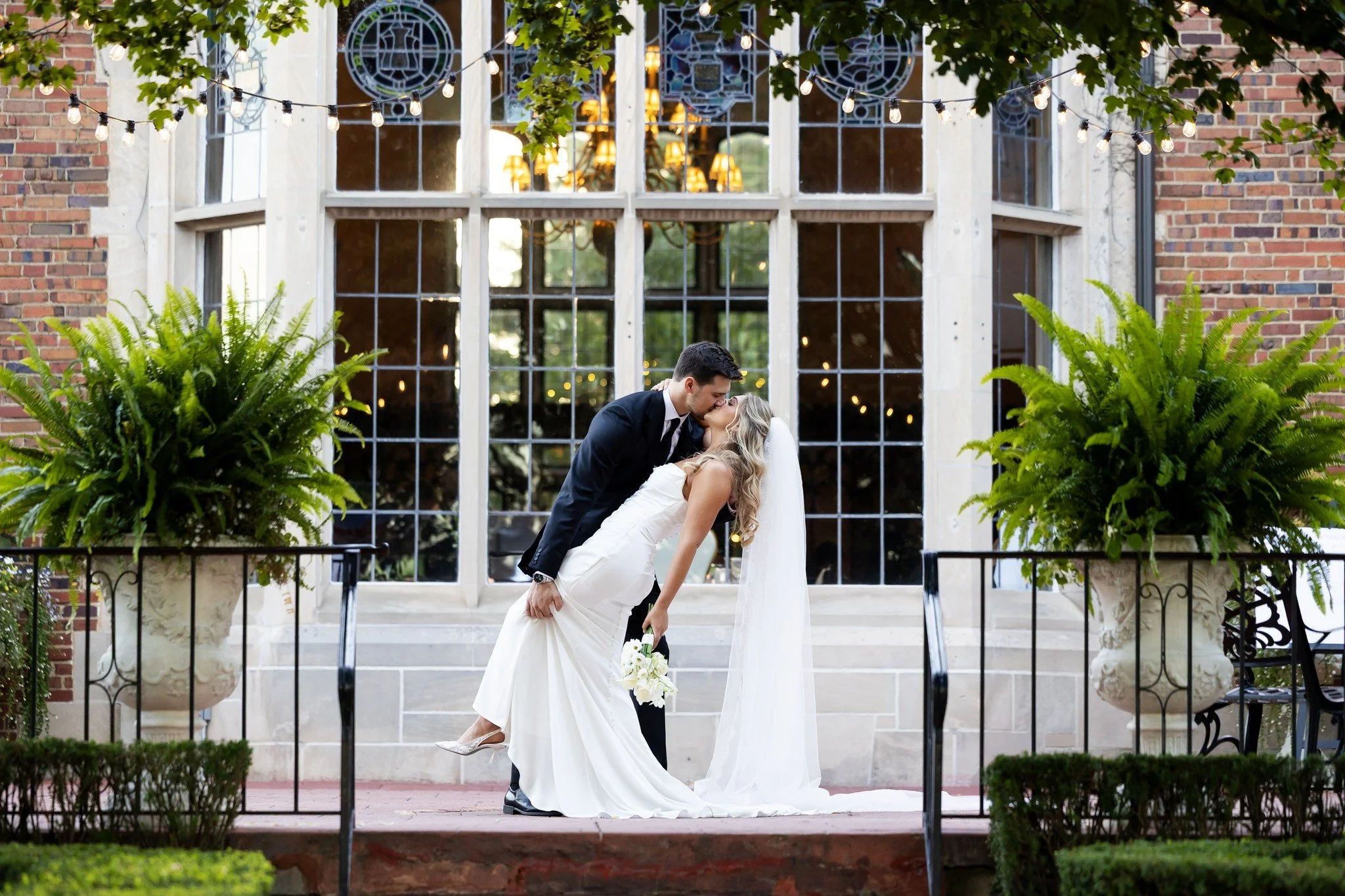 The groom dips the bride for a kiss on the terrace of Pine Knob Mansion in Clarkston, Michigan
