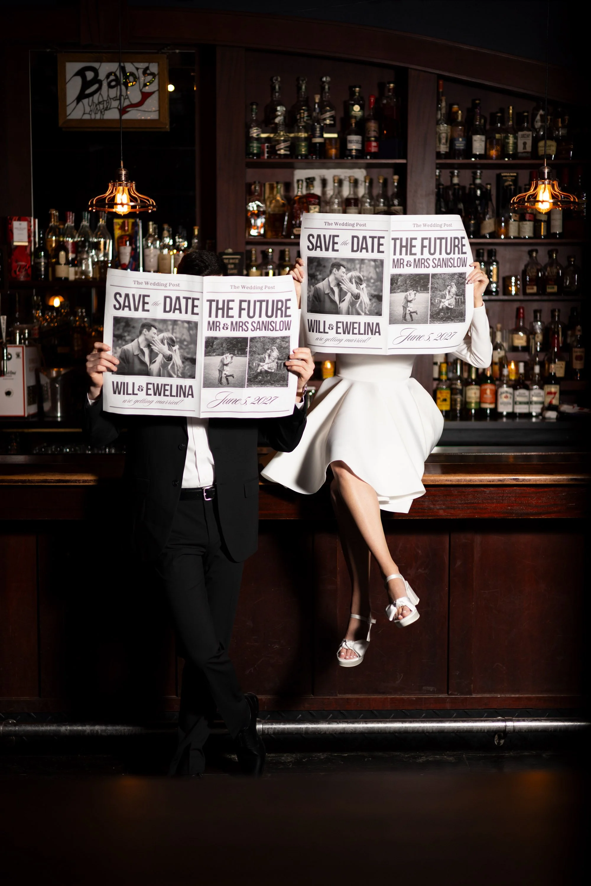 engaged couple holds customized “save the date” newspapers for their engagement session photos