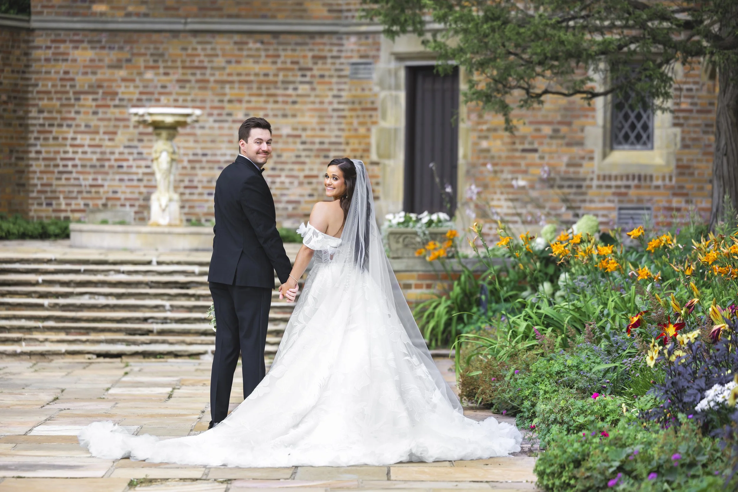 Bride and groom look back while walking away at Meadow Brook Hall in Rochester, Michigan