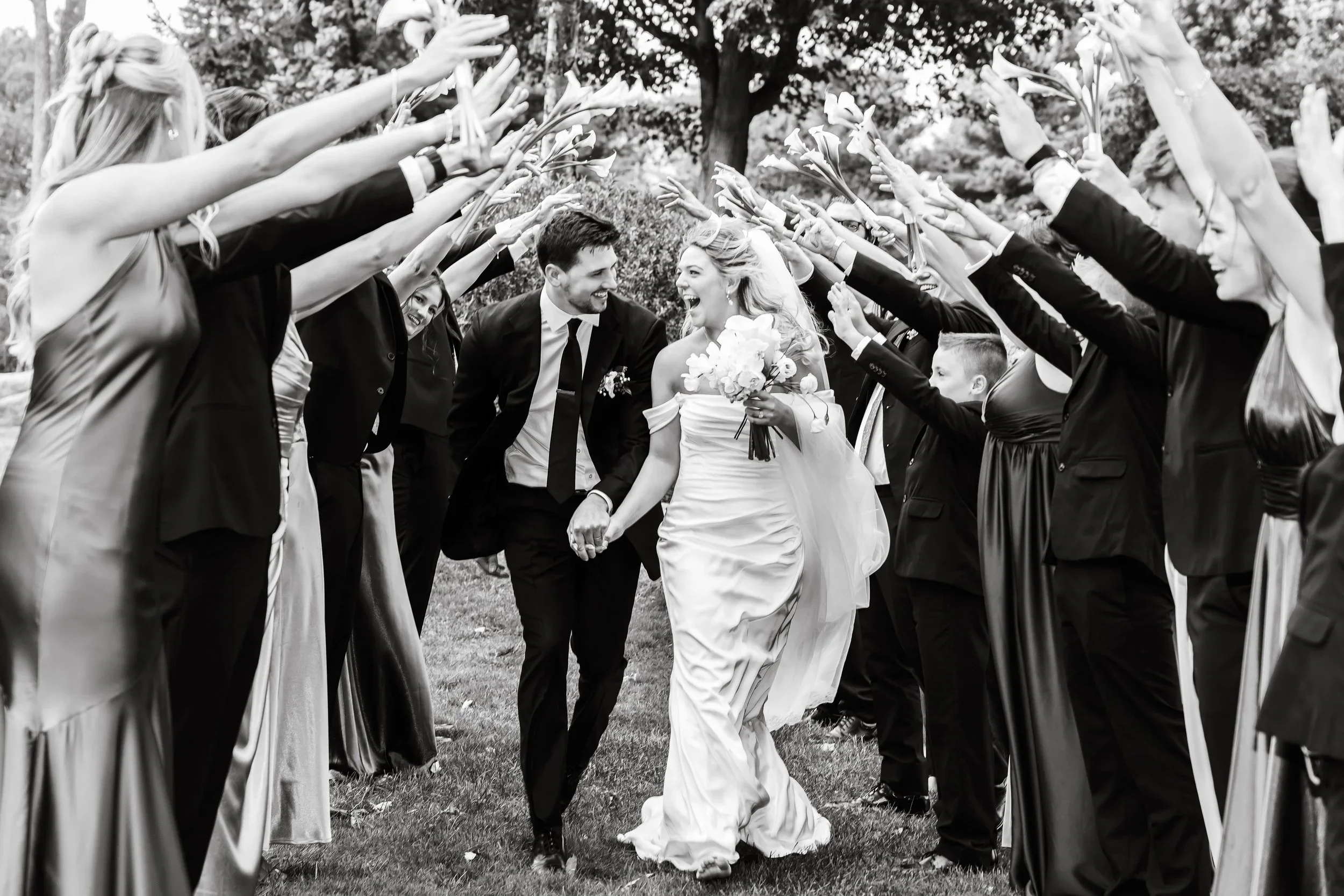 Bride and groom running together through tunnel of people at Pine Knob Mansion in Clarkston, Michigan