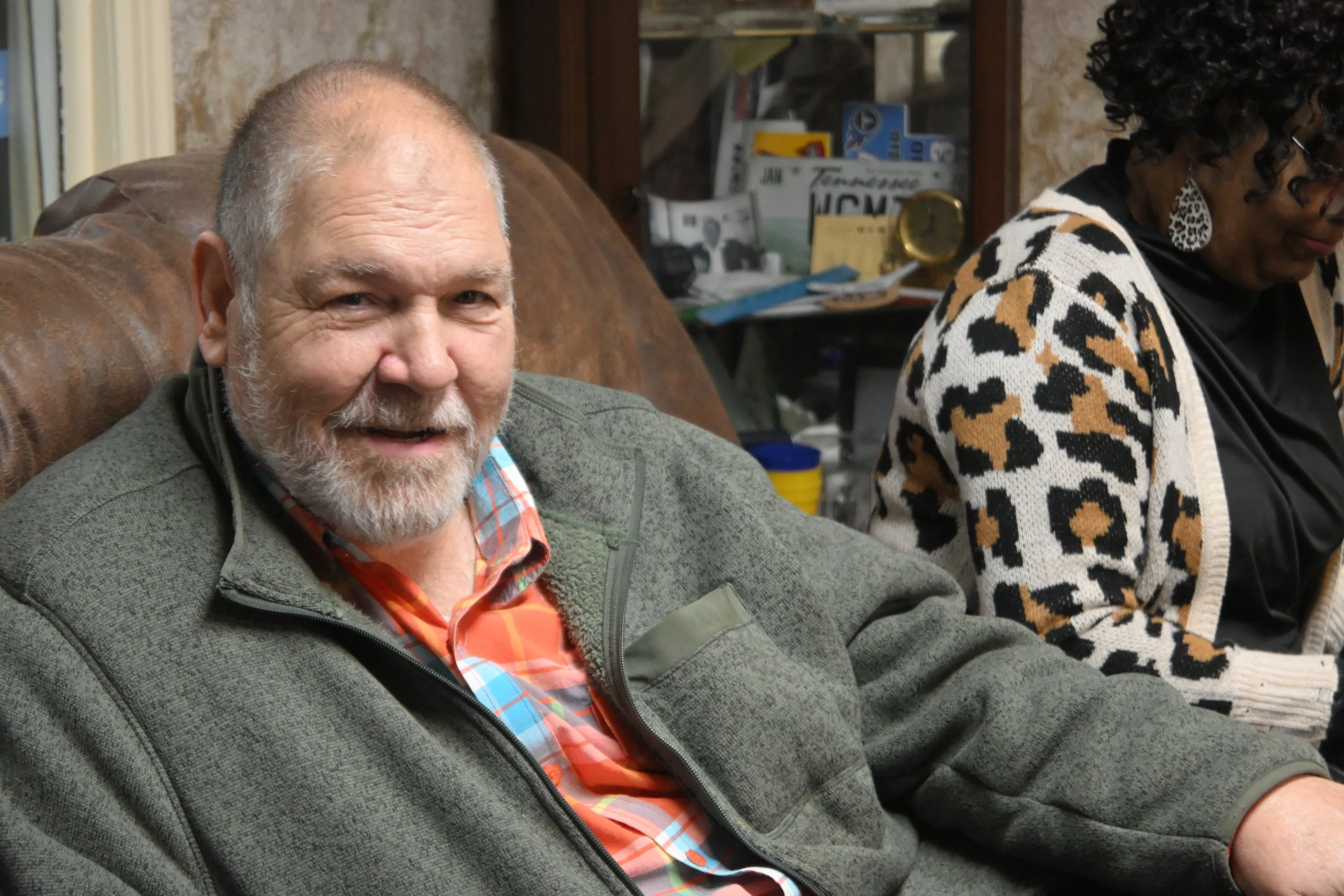 A man we support sitting on a couch in the lobby area, waiting for his turn to go the air during the SJCS Radiothon