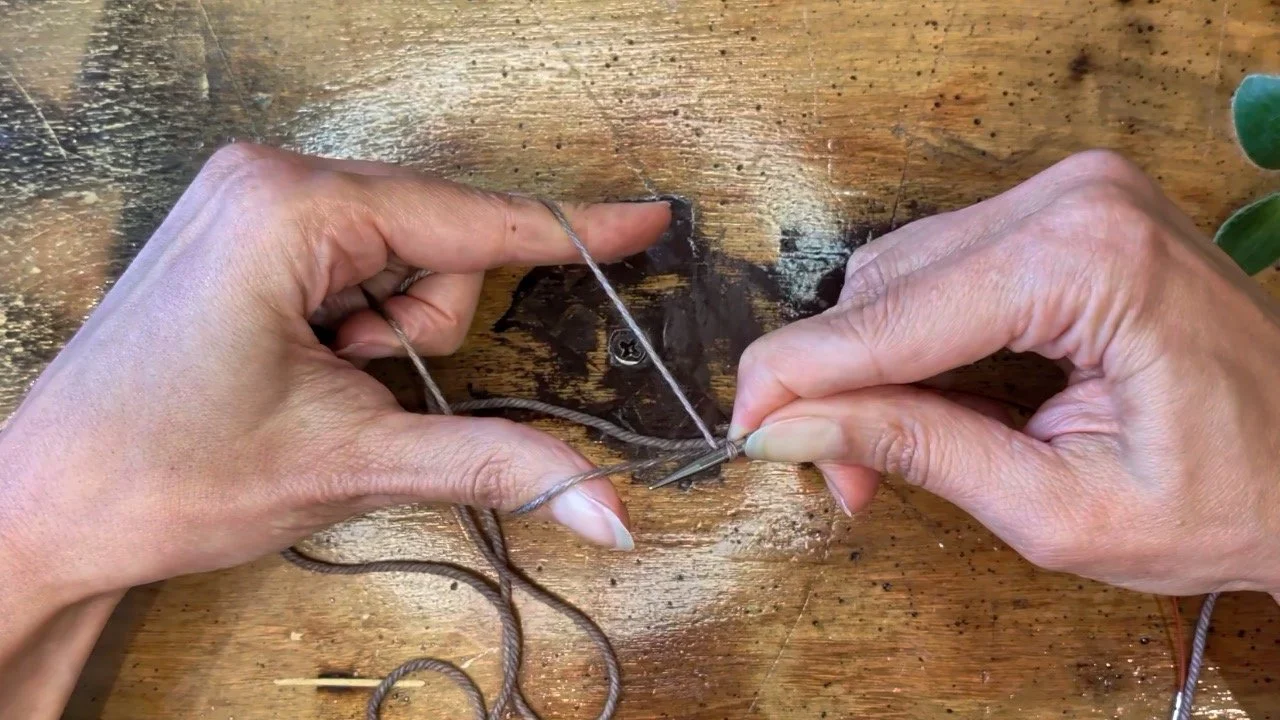 Bring the knitting needle forward over the thumb strand of yarn.