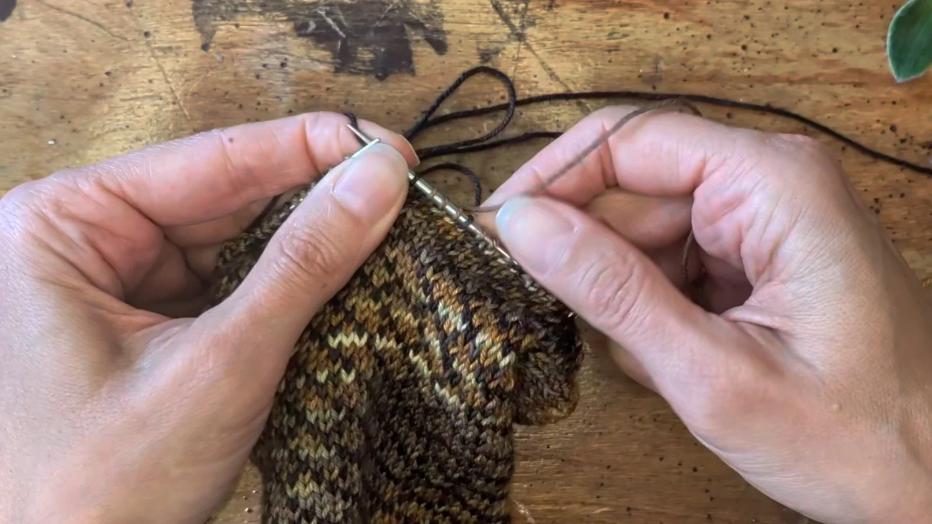 two hands show a stitches stretched out along the right knitting needle.