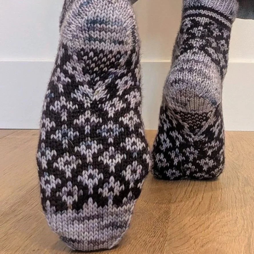 View of the sole of a colorwork knitted sock showing a Diamond Gusset construction with centered decreases for arch shaping.