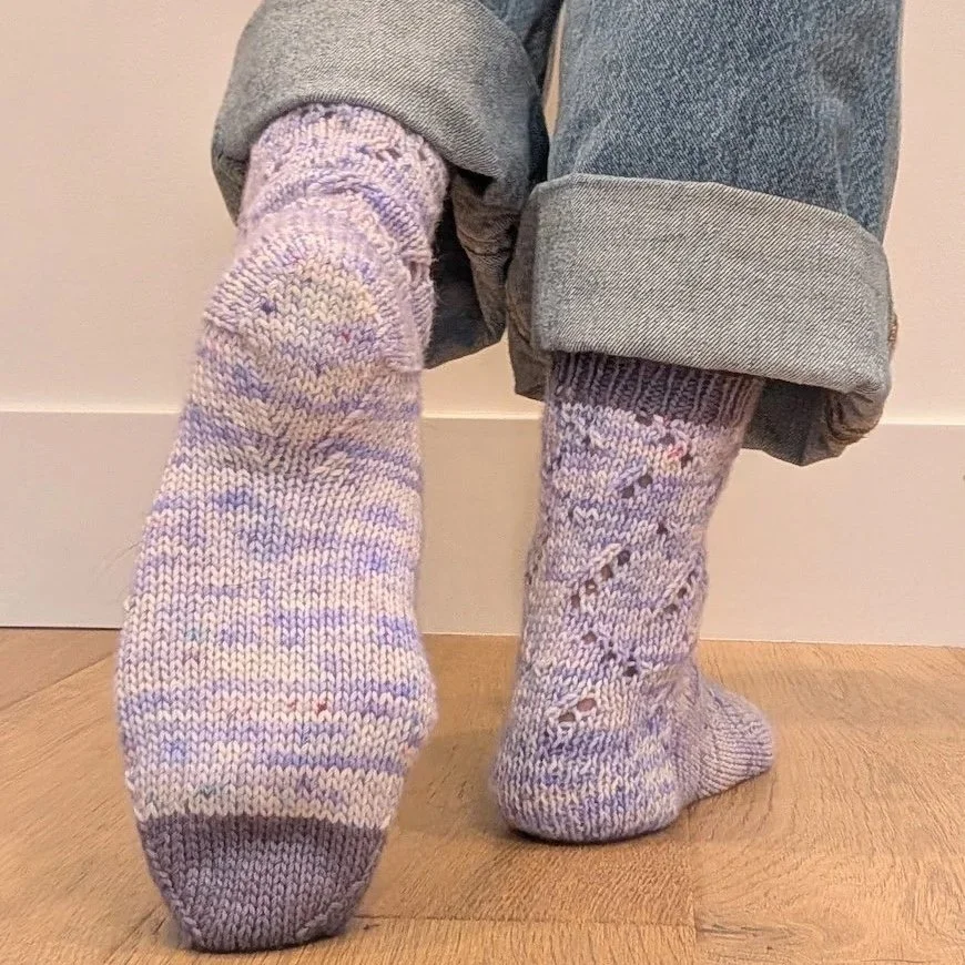 Close-up of a hand-knitted sock featuring a Double Gusset on a high-arched foot, showing the two distinct decrease lines for a snug fit.
