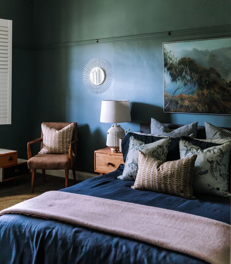  AFTER: The guest bedroom is now a warm and inviting guest’s retreat. The blue-green wall colour envelopes the room to create a cosy space for guests. Darker navy tones and pops of brass and mustard have been used to create a restful space. 