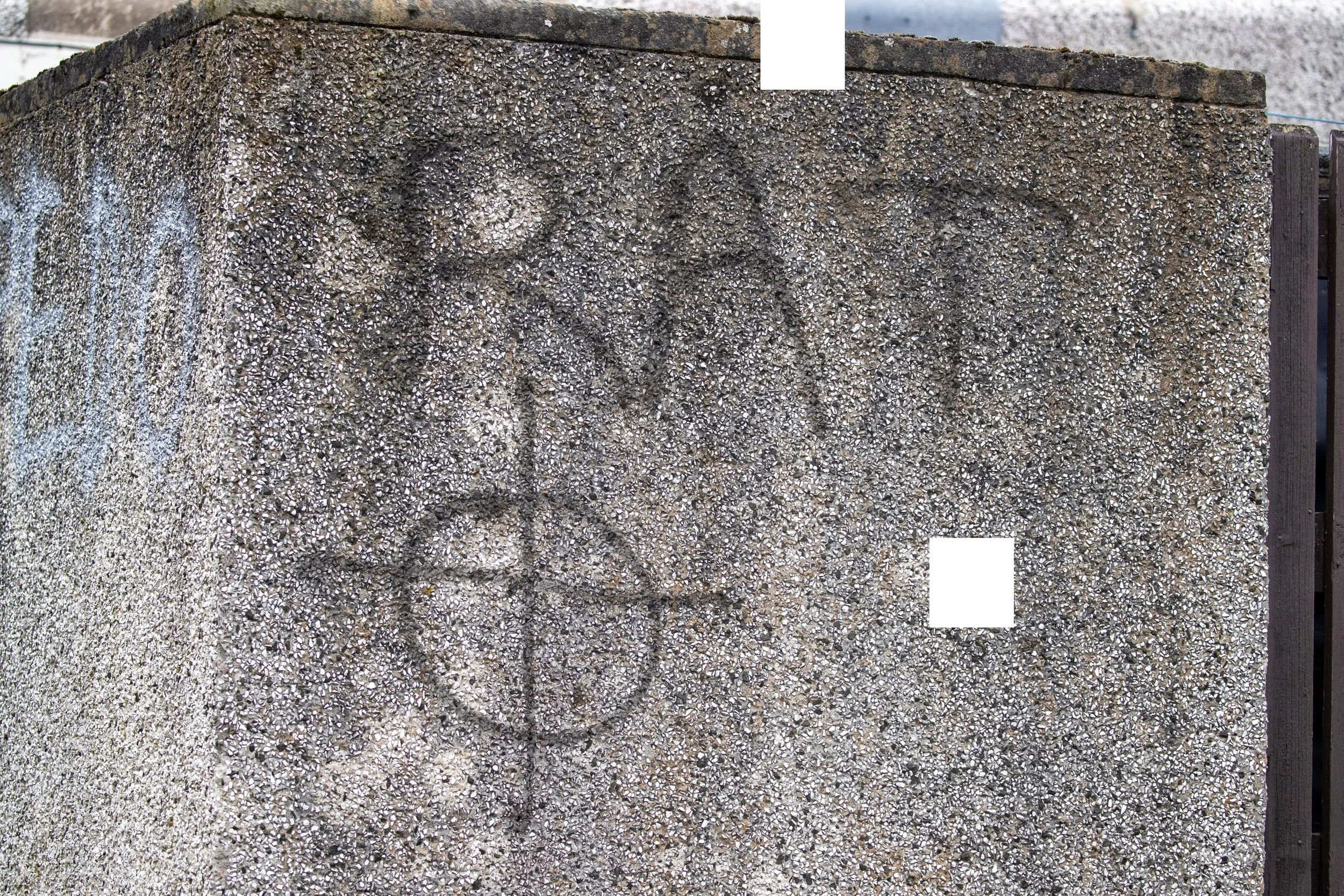 Graffiti on a rough concrete wall, featuring a peace sign, the word 'LOVE,' and a smiling face.