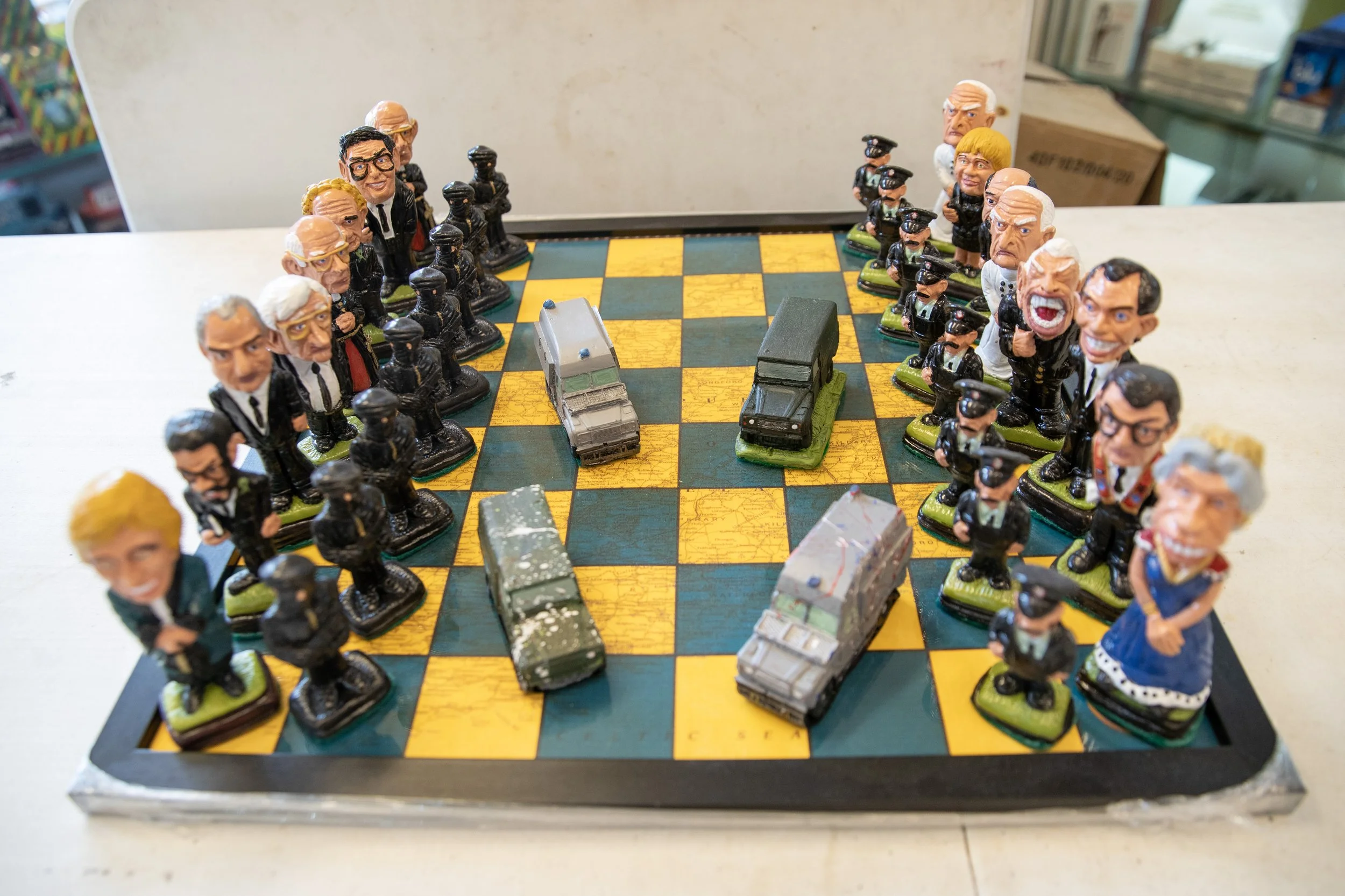 A chessboard with figurines of politicians and military vehicles arranged as chess pieces.