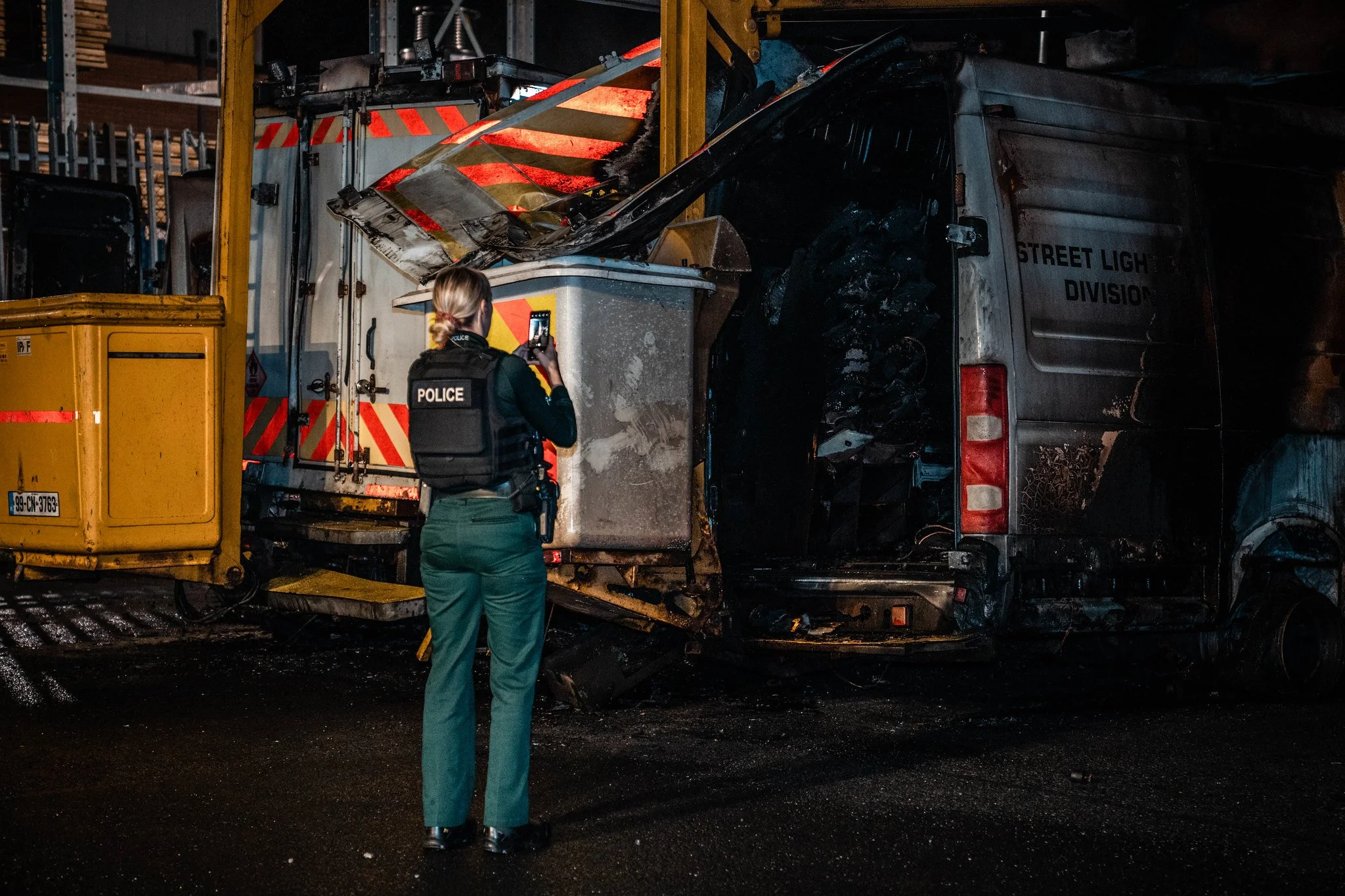 Police officer documenting the burnt wreckage of a street light division truck involved in a fire