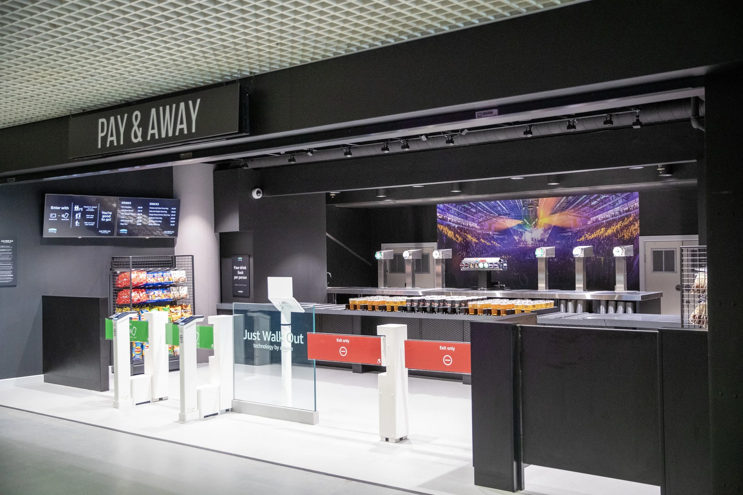 An empty airport pay and away counter area with vending machines, an entrance, and a neon sign.