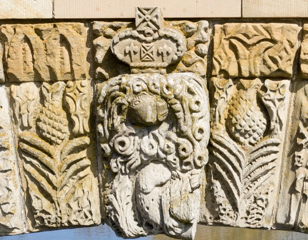 Stone carving on a bridge of a royal rat creature.
