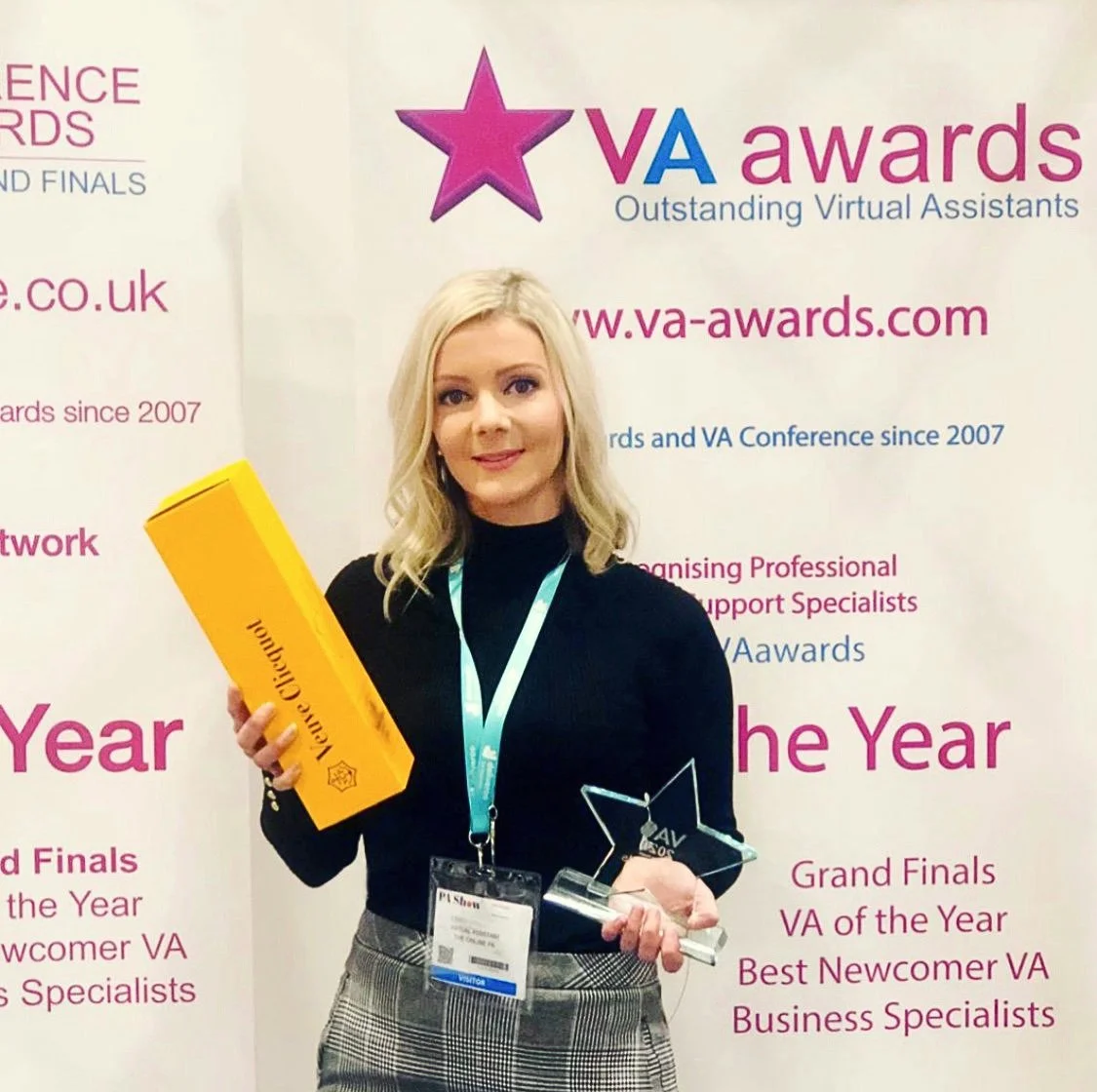 Woman holding a yellow award box and a glass star-shaped trophy at the VA Awards event.