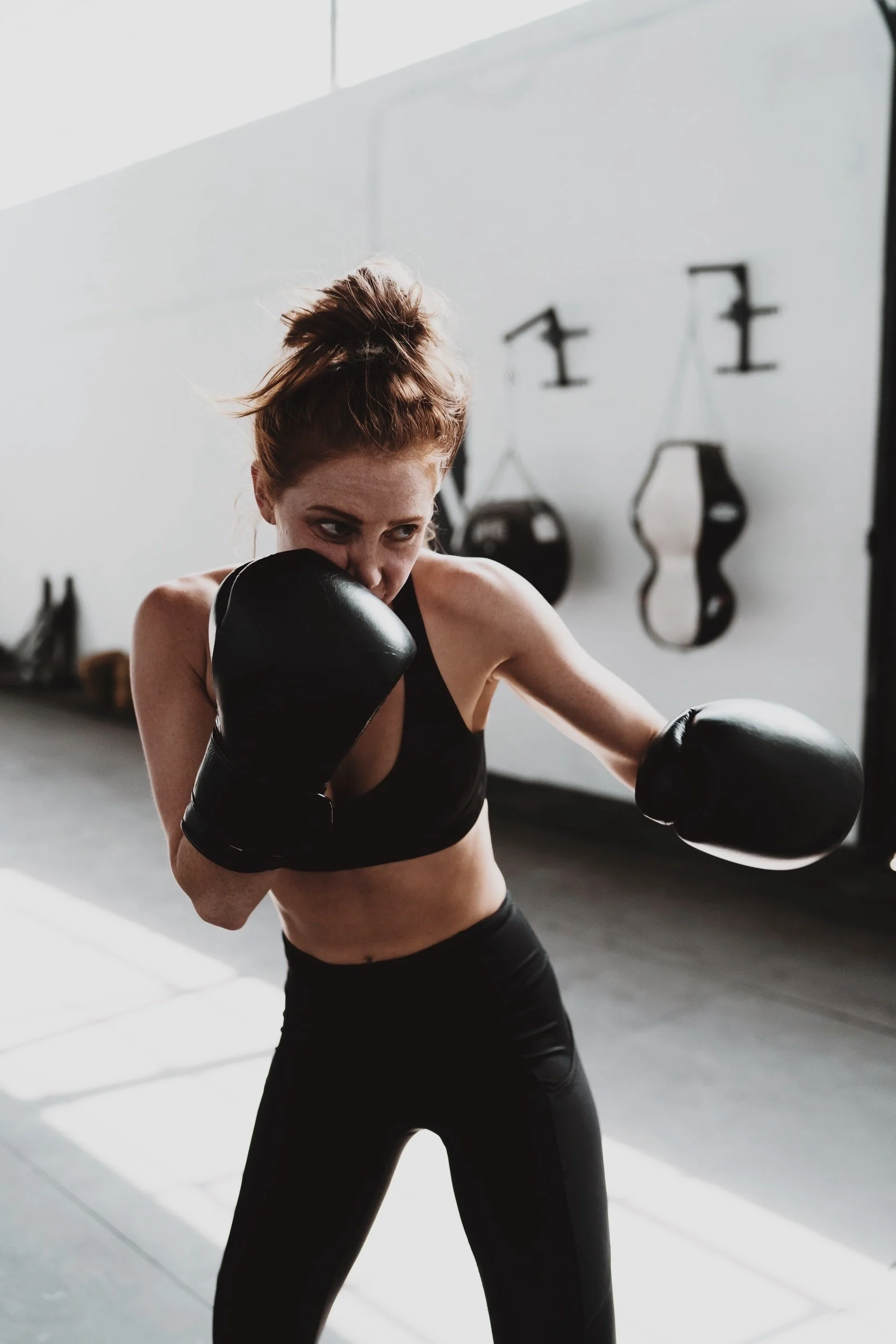 Woman in sportswear and boxing gloves practicing boxing moves.