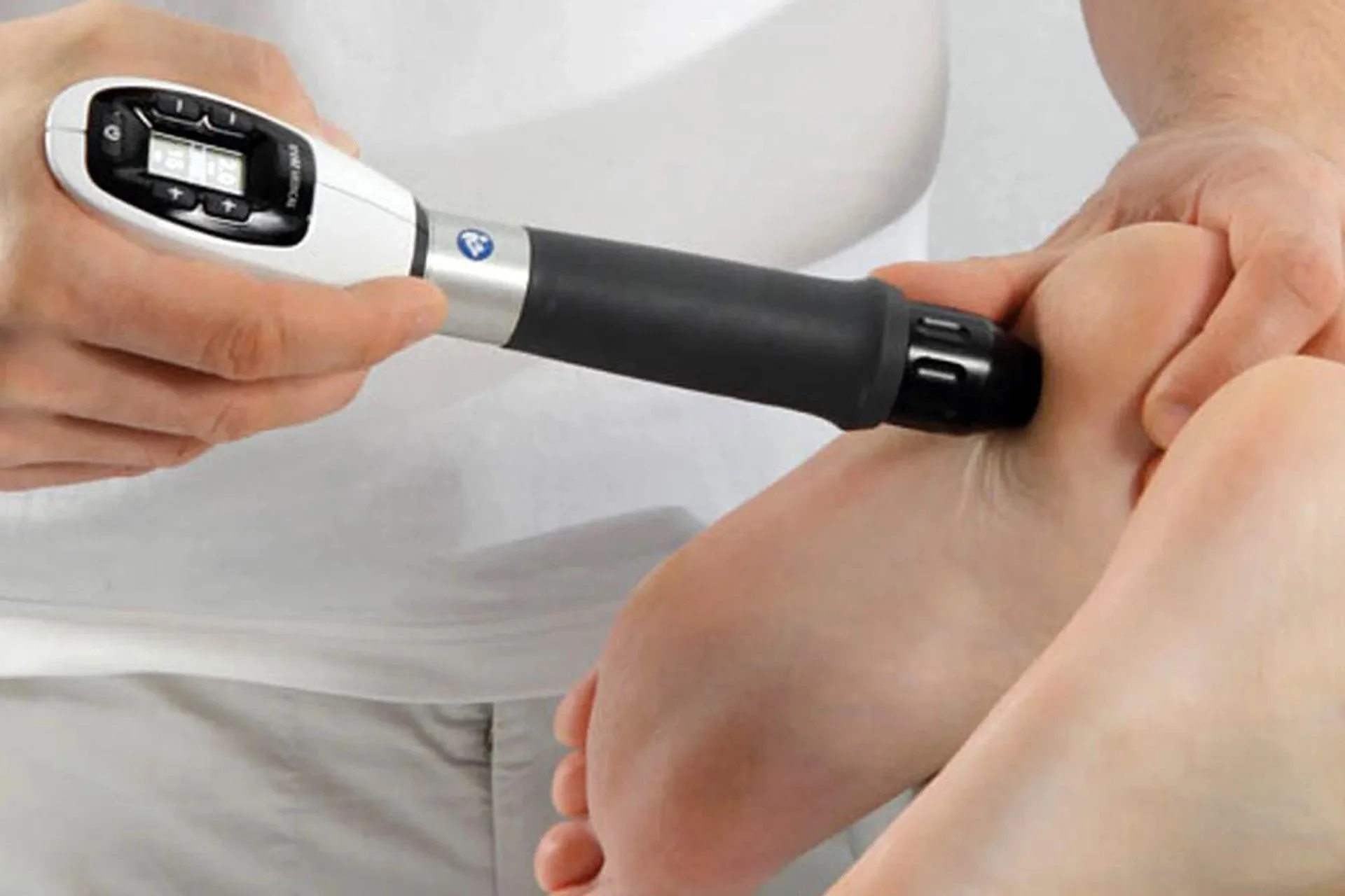 Person using a shockwave therapy device on a foot.