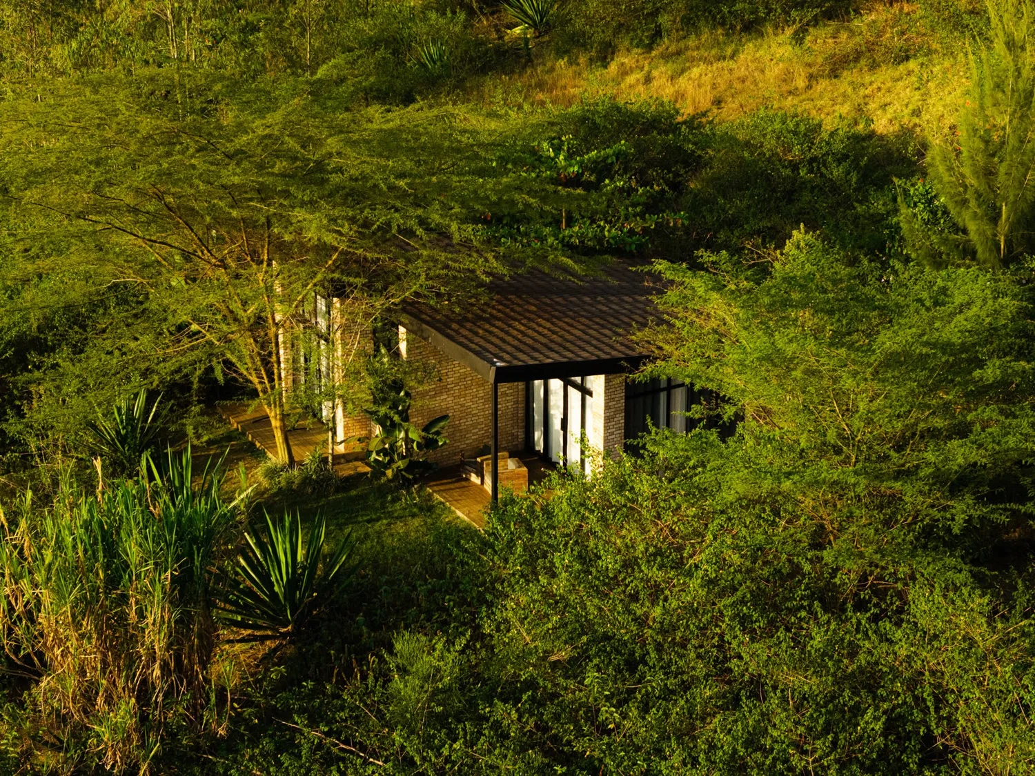 A rammed-earth unit among acacia trees above Lake Muhazi